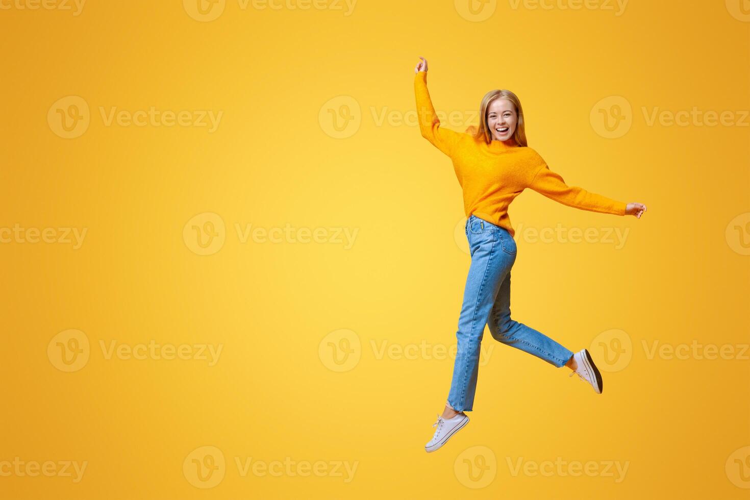 Last exam. Portrait of cute teen girl jumping on orange background, copy space photo