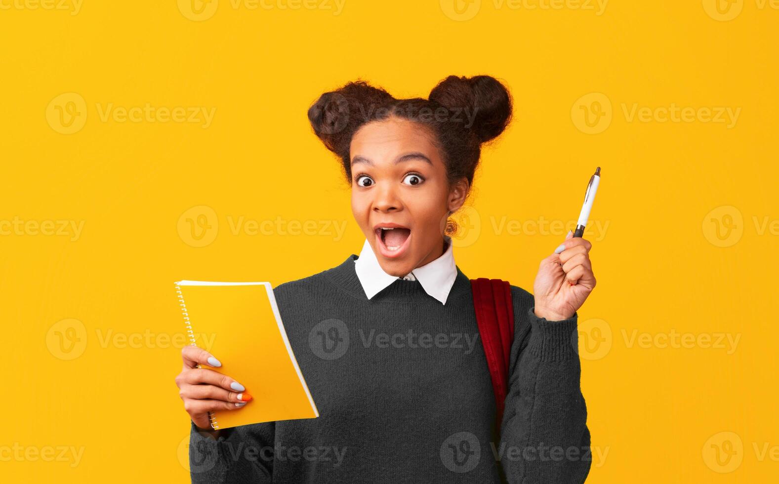 Eureka. Close up portrait of intelligent black girl with opened mouth holding notebook, pointing up with pen, copyspace photo