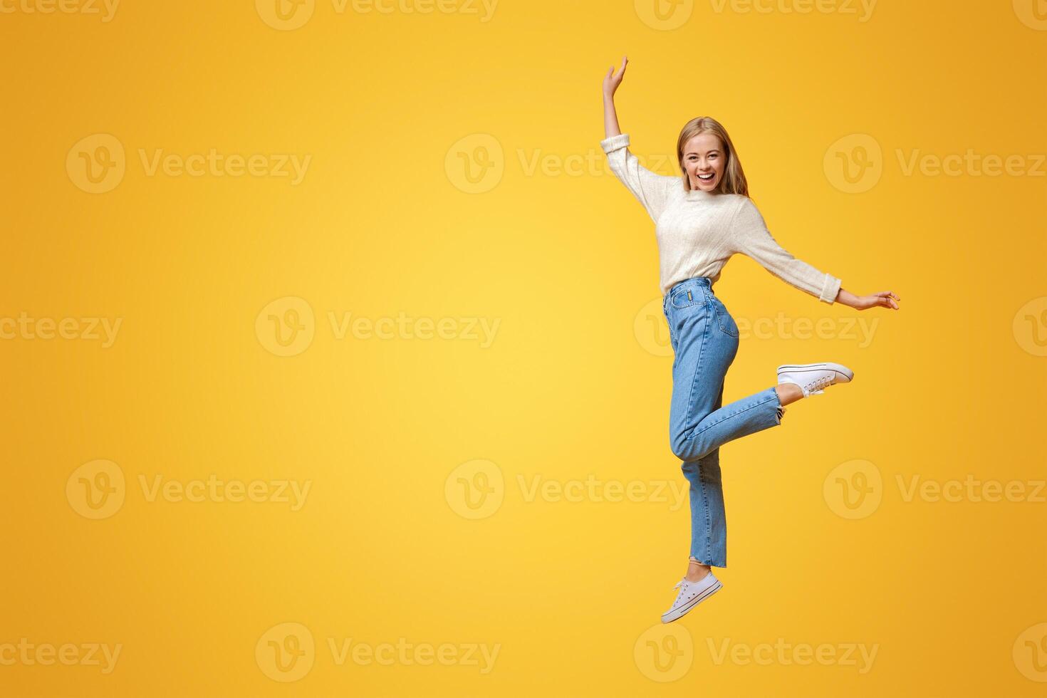 Carefree youth. Happy young girl jumping on air and smiling over orange background photo