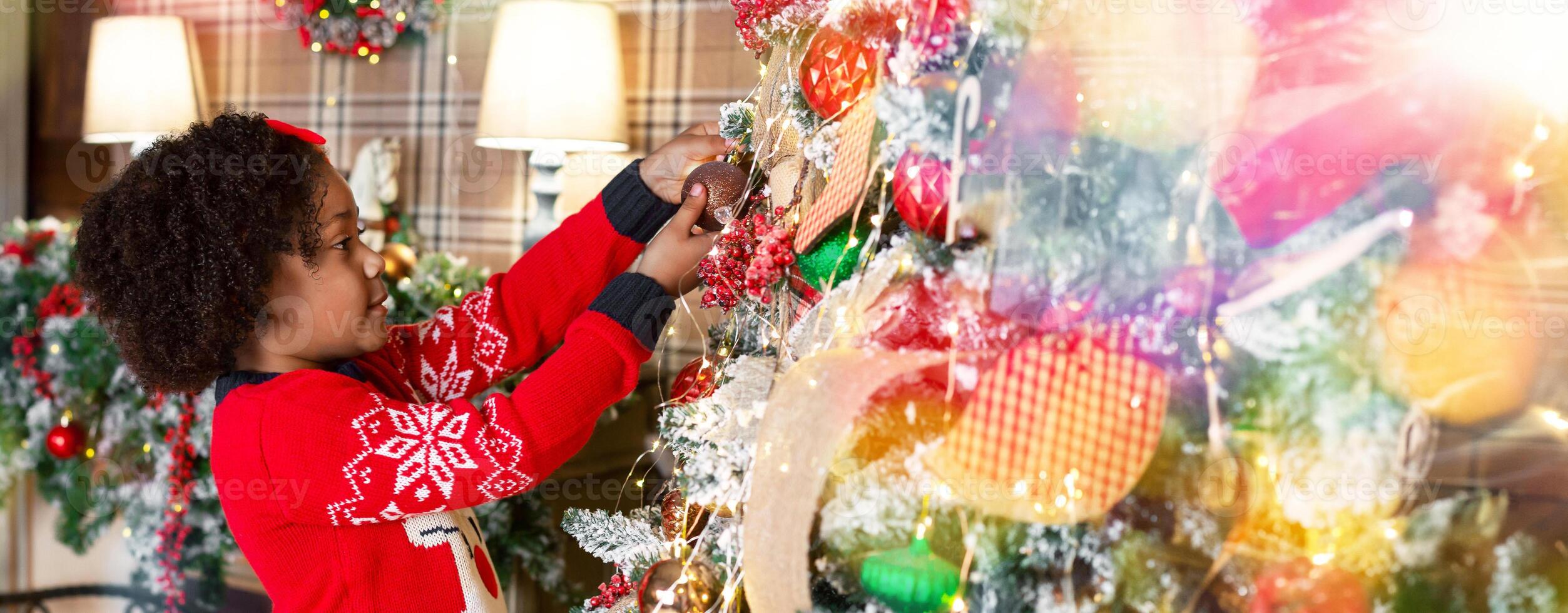 Xmas tradition. Cute little african american girl decorating Christmas tree at home, panorama photo