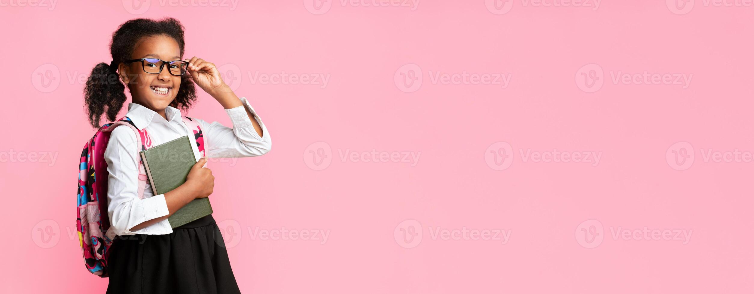 Back To School. Happy Afro Elementary Student Girl Holding Books Smiling At Camera On Yellow Studio Background. Free Space photo