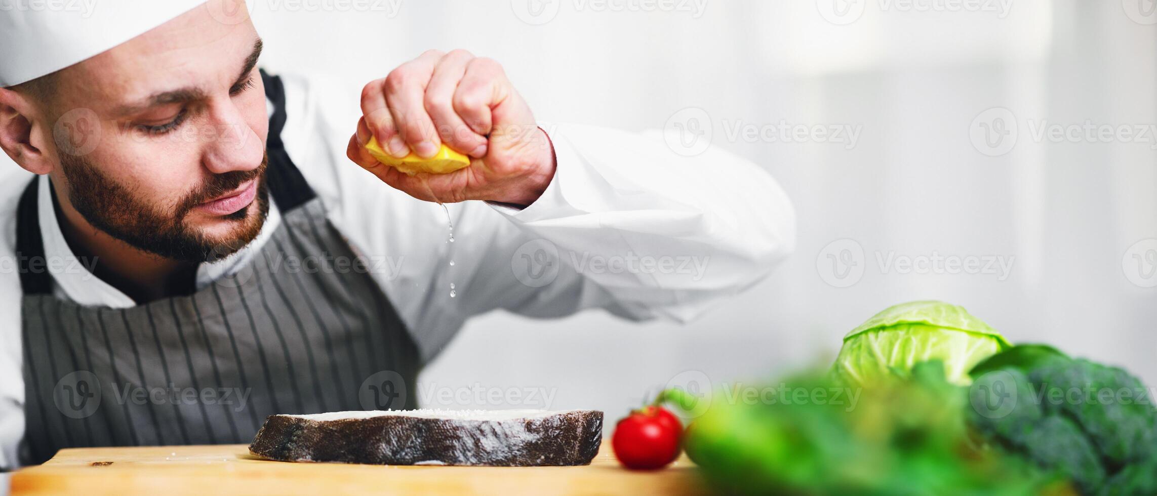 Cooking Fish. Chef Man Squeezing Lemon Juice On Salmon Steak Standing In Restaurant Kitchen. Selective Focus photo
