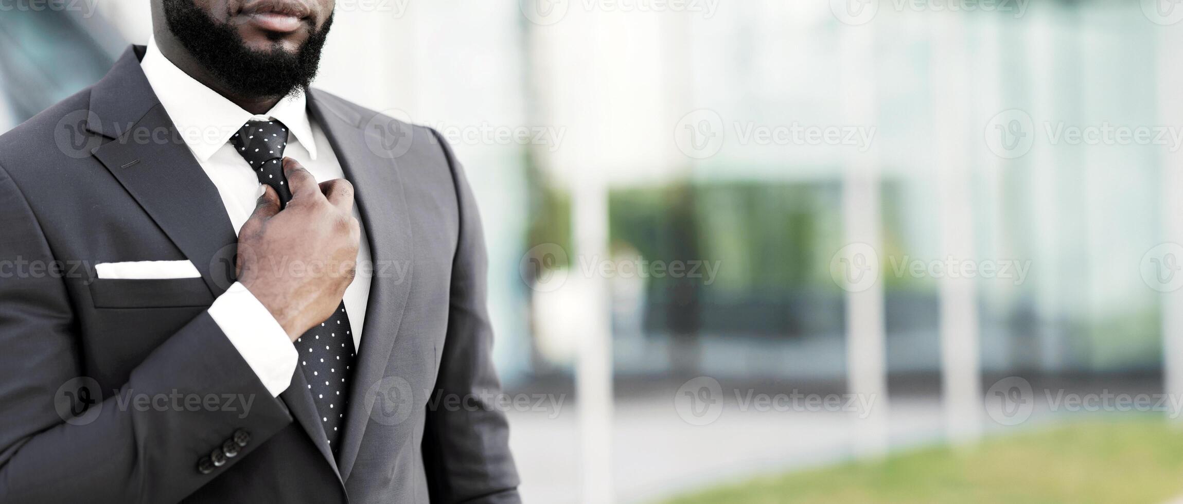Unrecognizable Black Man Adjusting Necktie Standing Outdoor In City. Successful Business Career. Cropped, Copy Space photo