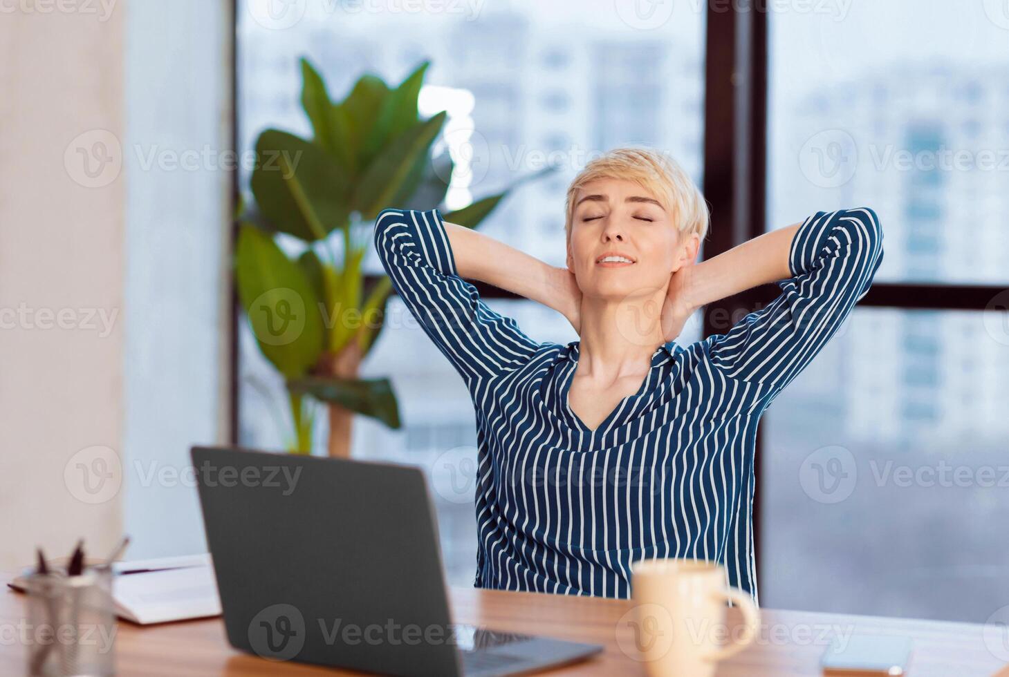 Relaxed Businesswoman Sitting Holding Hands Behind Head Relaxing Having Break At Work In Modern Office. Selective Focus photo