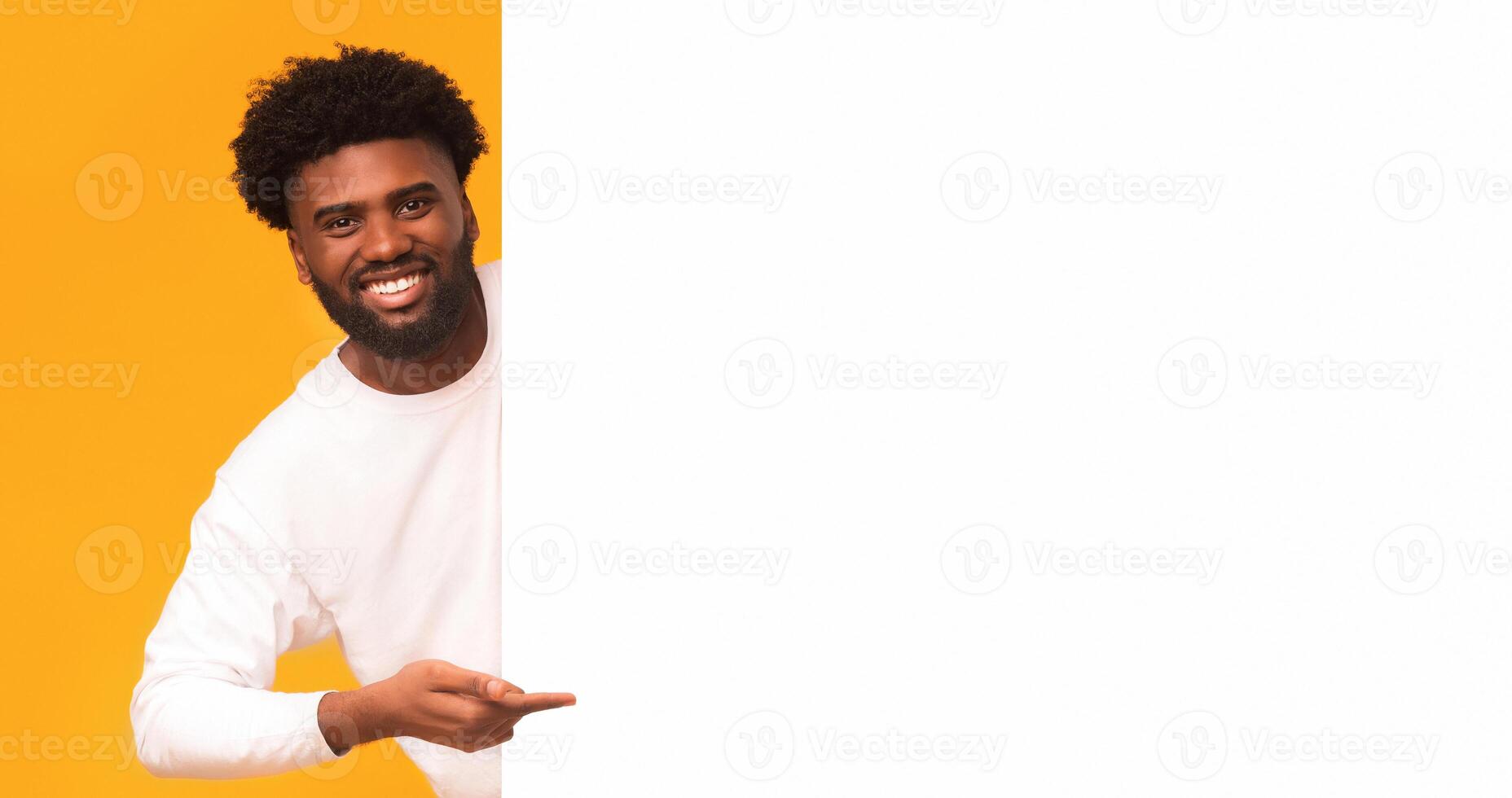 Empty space for advertising. Cheerful african guy pointing at big blank board, orange background, panorama photo