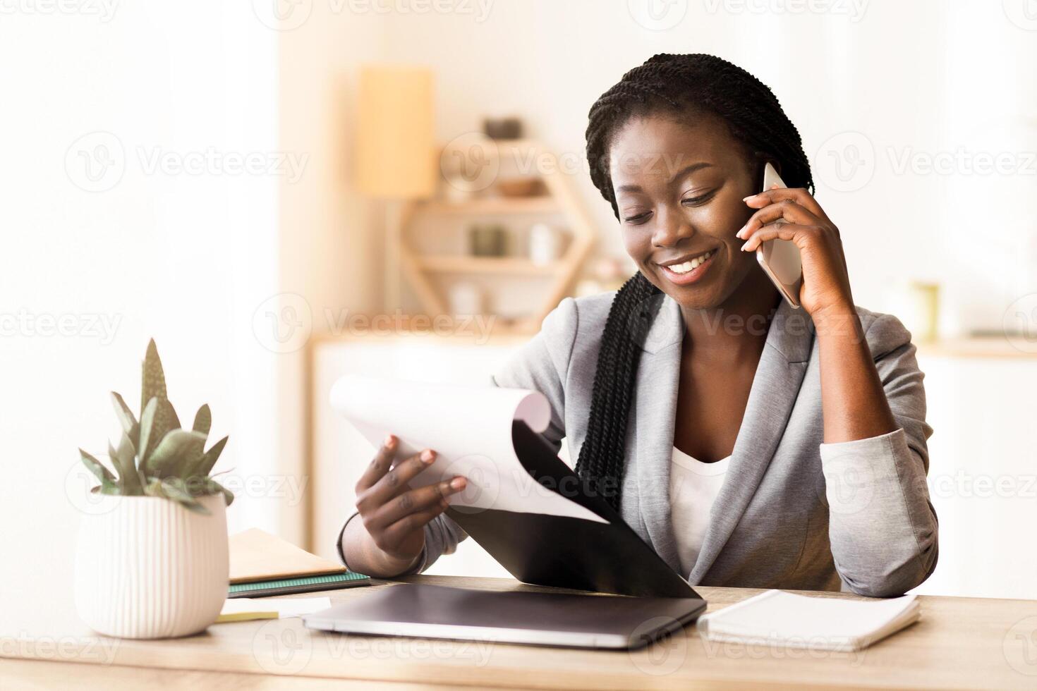Business consulting. Black female manager making phone call and checking reports in modern office. photo