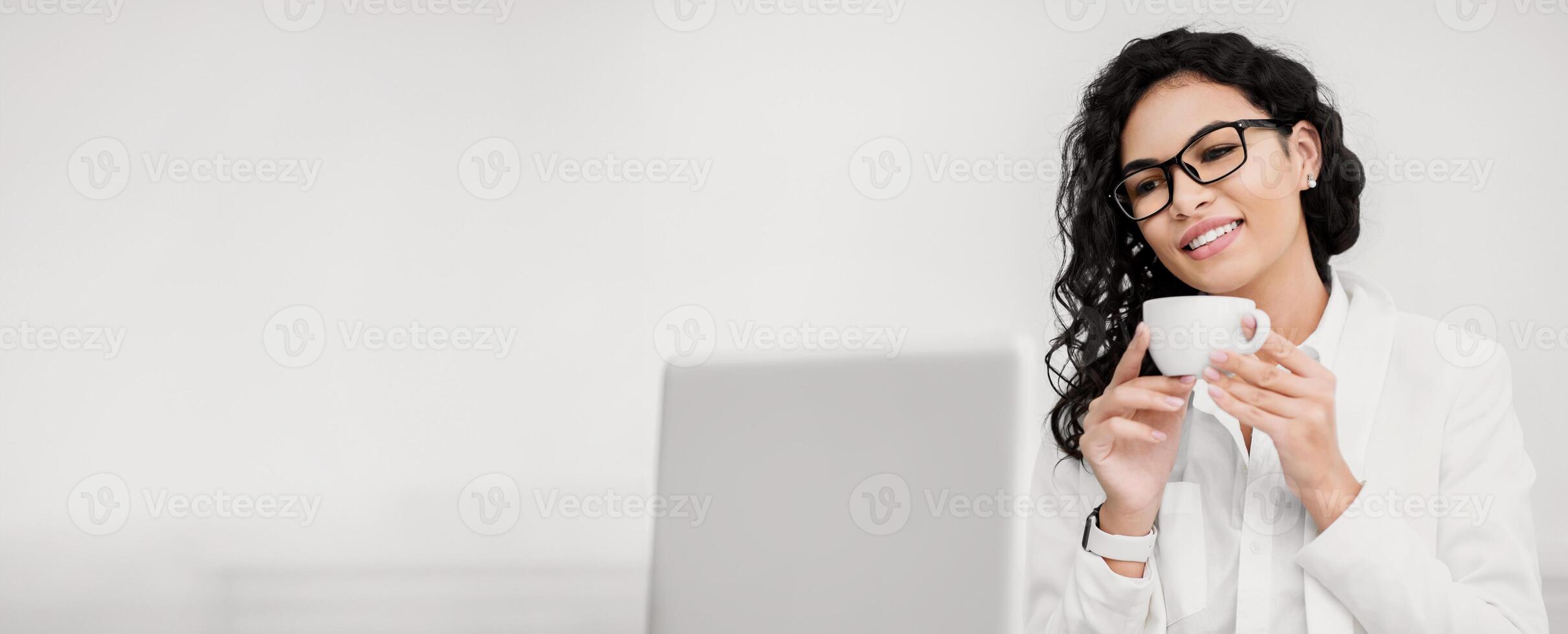Time For Break. Happy brazilian teacher drinking coffee and watching videos on laptop, copyspace photo
