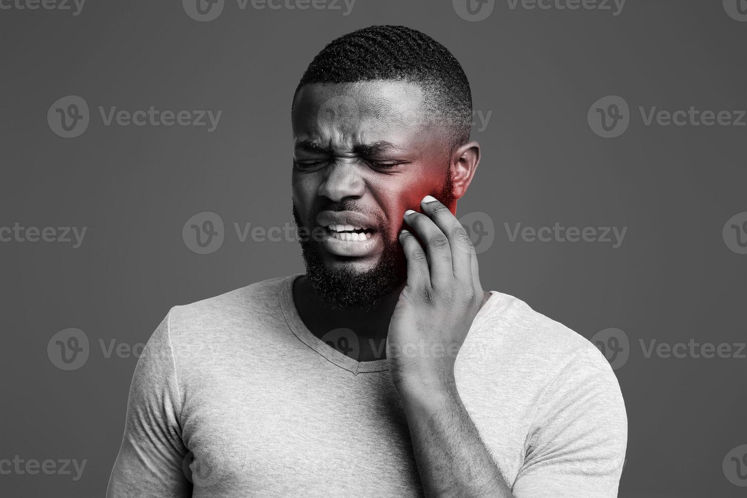 Sad afro man having gum problems, touching his cheek, white studio background, tooth disease concept photo
