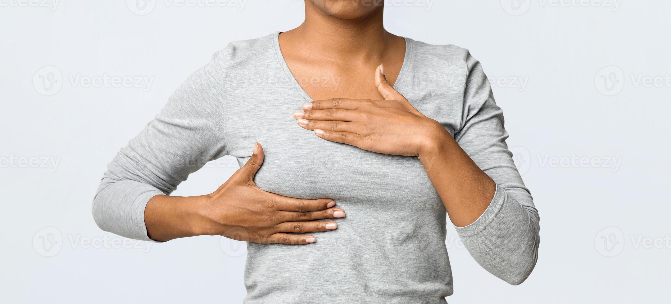 Breast cancer. Young african woman feeling breast pain, touching her chest, cropped photo