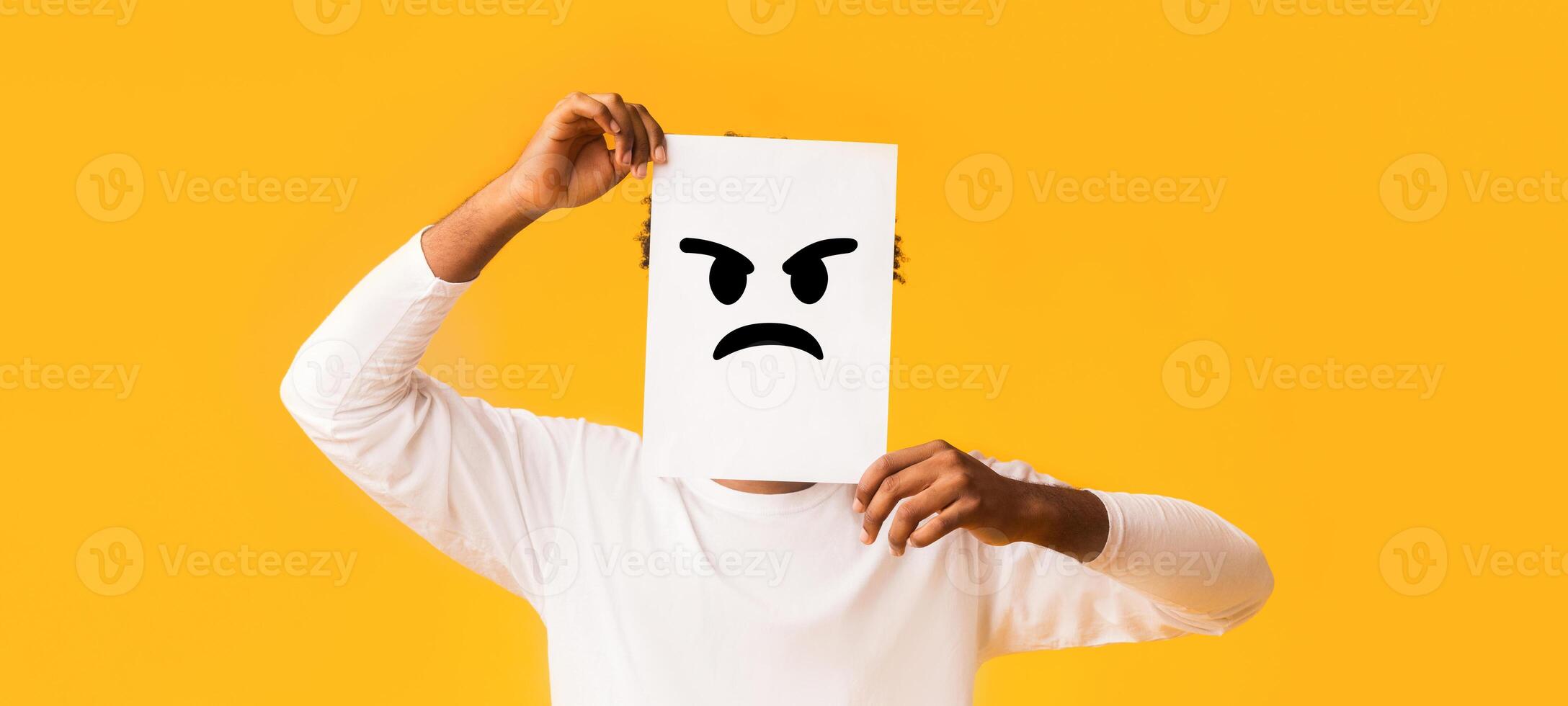 Putting smiling face on. Black man holding paper with smiley face printed on over orange background, happiness and joy concept photo