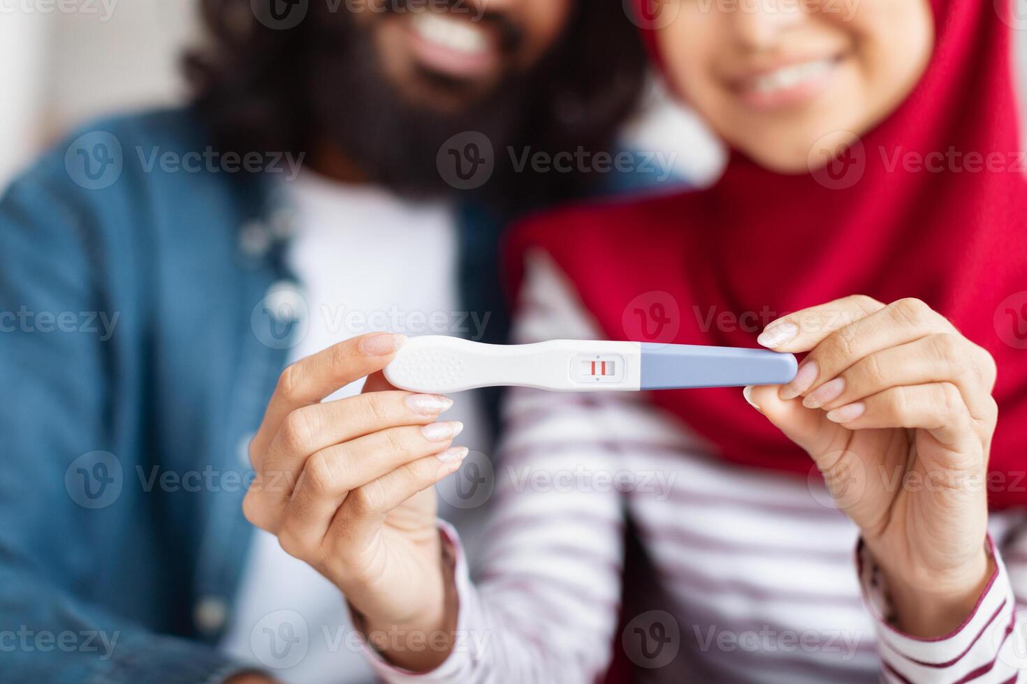 Cropped of muslim man and woman are standing together, each holding pregnancy test in their hands, closeup photo