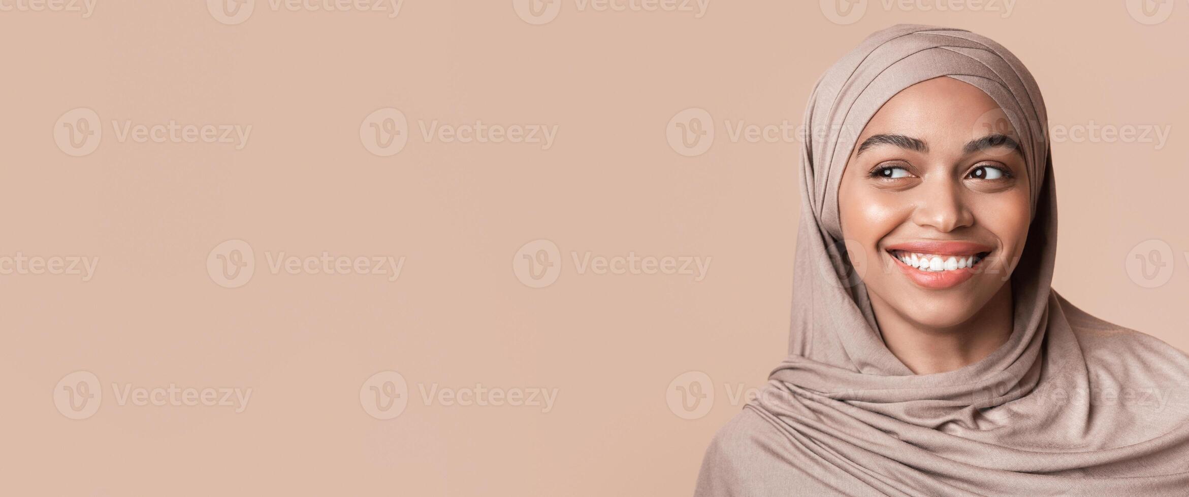 Portrait of beautiful black girl in hijab looking aside at copy space over yellow background, closeup photo