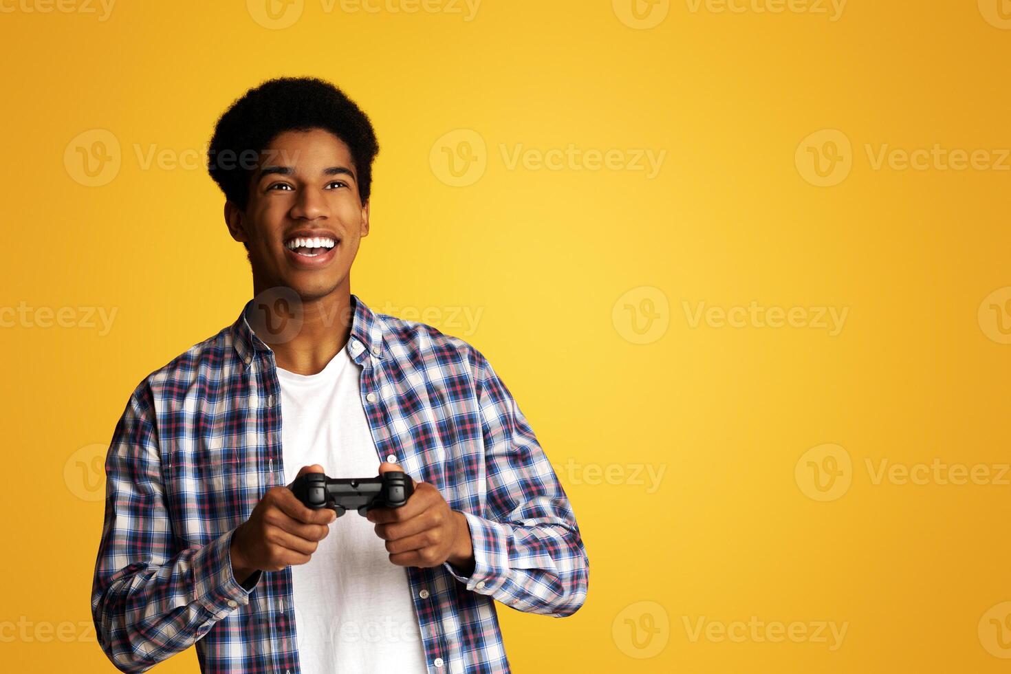 Gambling Addiction. Excited Guy Holding Joystick and Playing Games, Yellow Background photo
