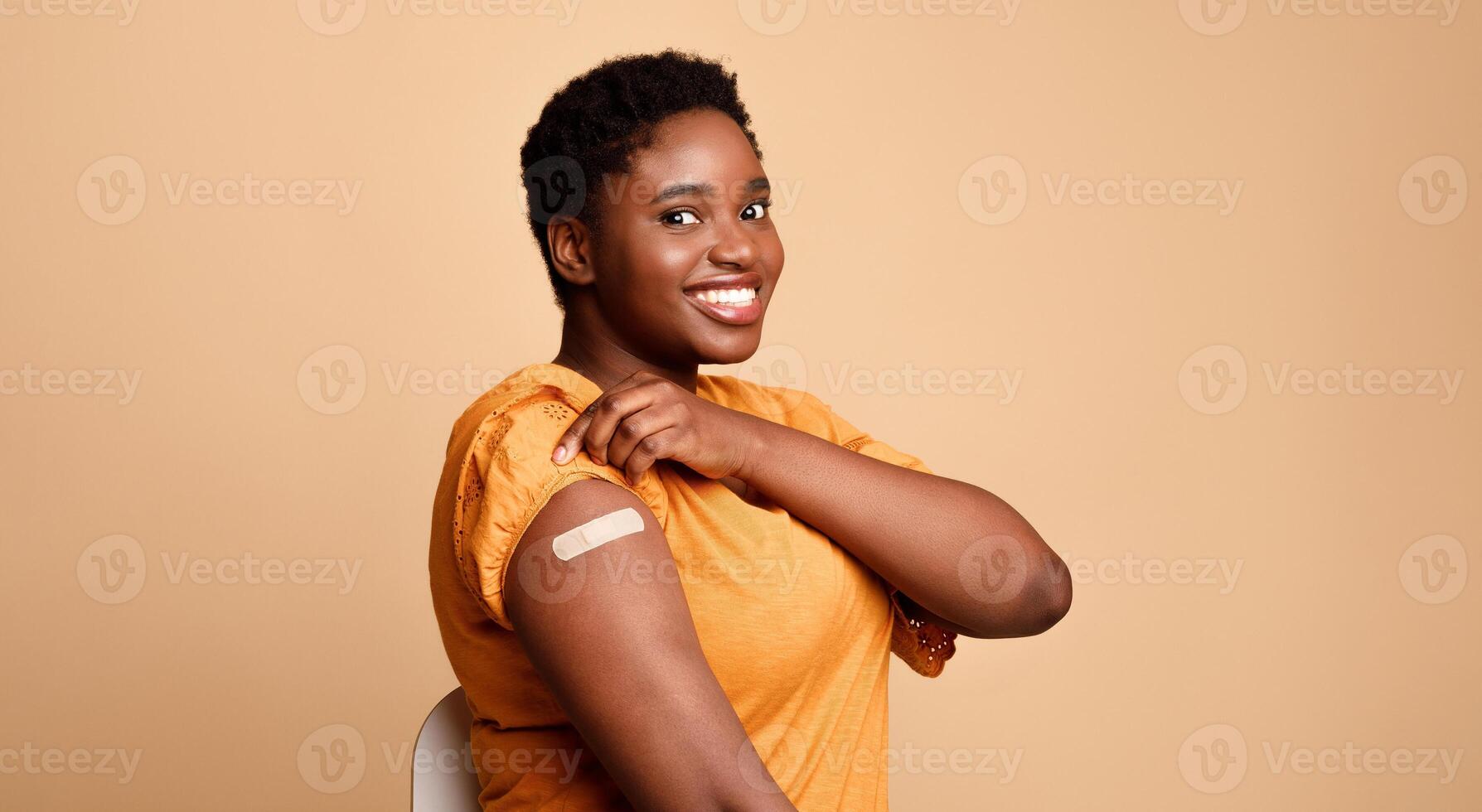 Successful Coronavirus Vaccination. Black Woman Showing Vaccinated Arm After Covid-19 Vaccine Injection Shot Posing Smiling To Camera On Beige Background. Corona Virus Immunization Concept. Panorama photo