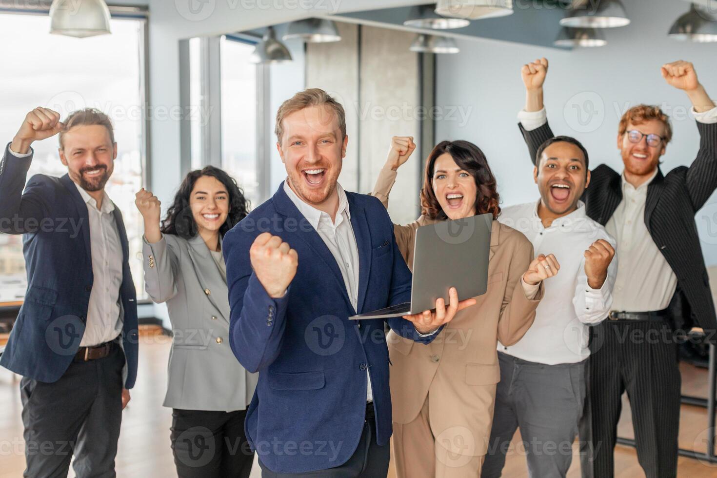 A group of diverse business professionals celebrates a successful project in their modern office. The team is ecstatic, with smiles and raised fists, expressing their shared joy. photo