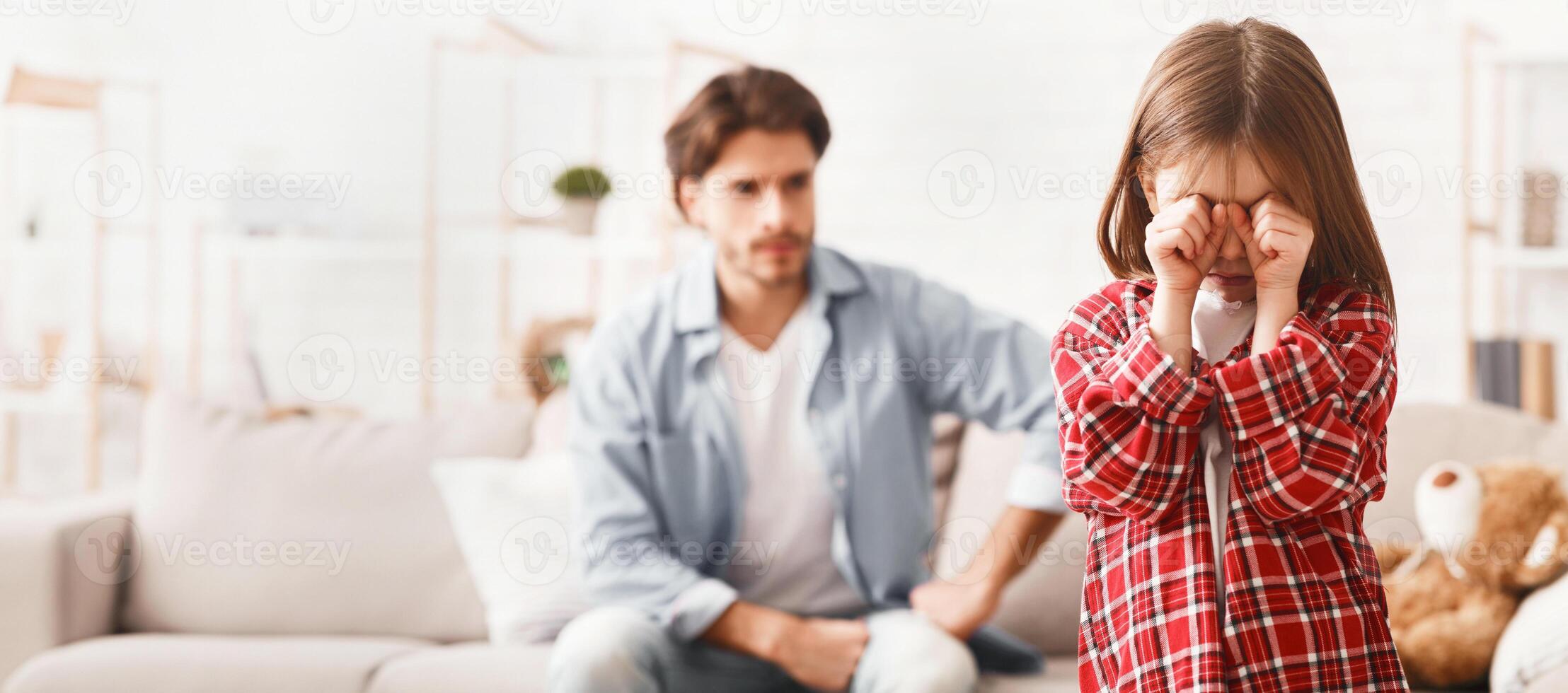 Quarrel With Father. Little girl crying after arguing wIth daddy, angry man on background photo