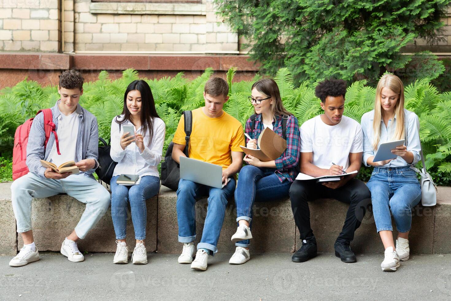 College students studying in university campus with books and devices, preparing for exams photo