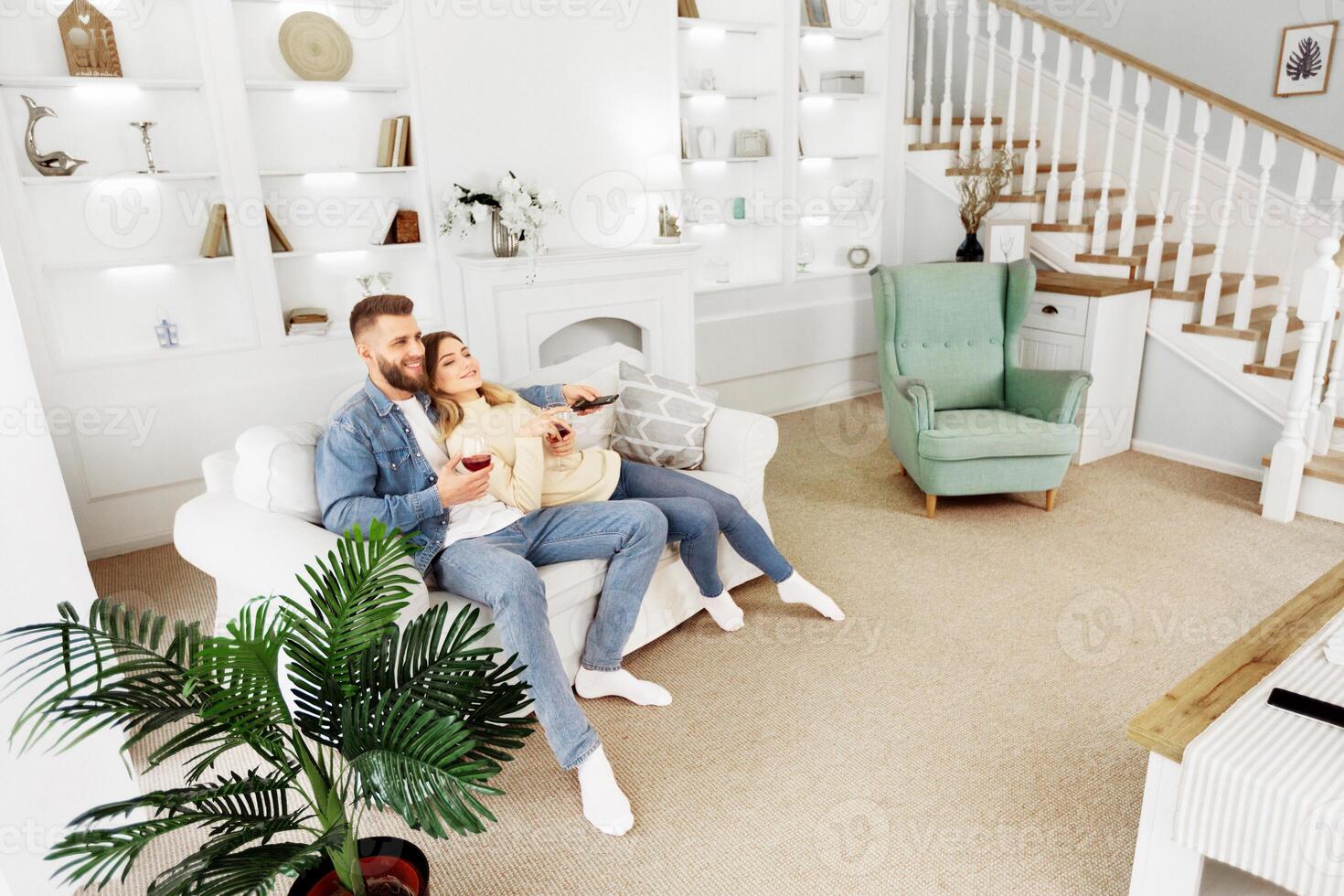 A man and a woman are seated on a couch in a living room. photo