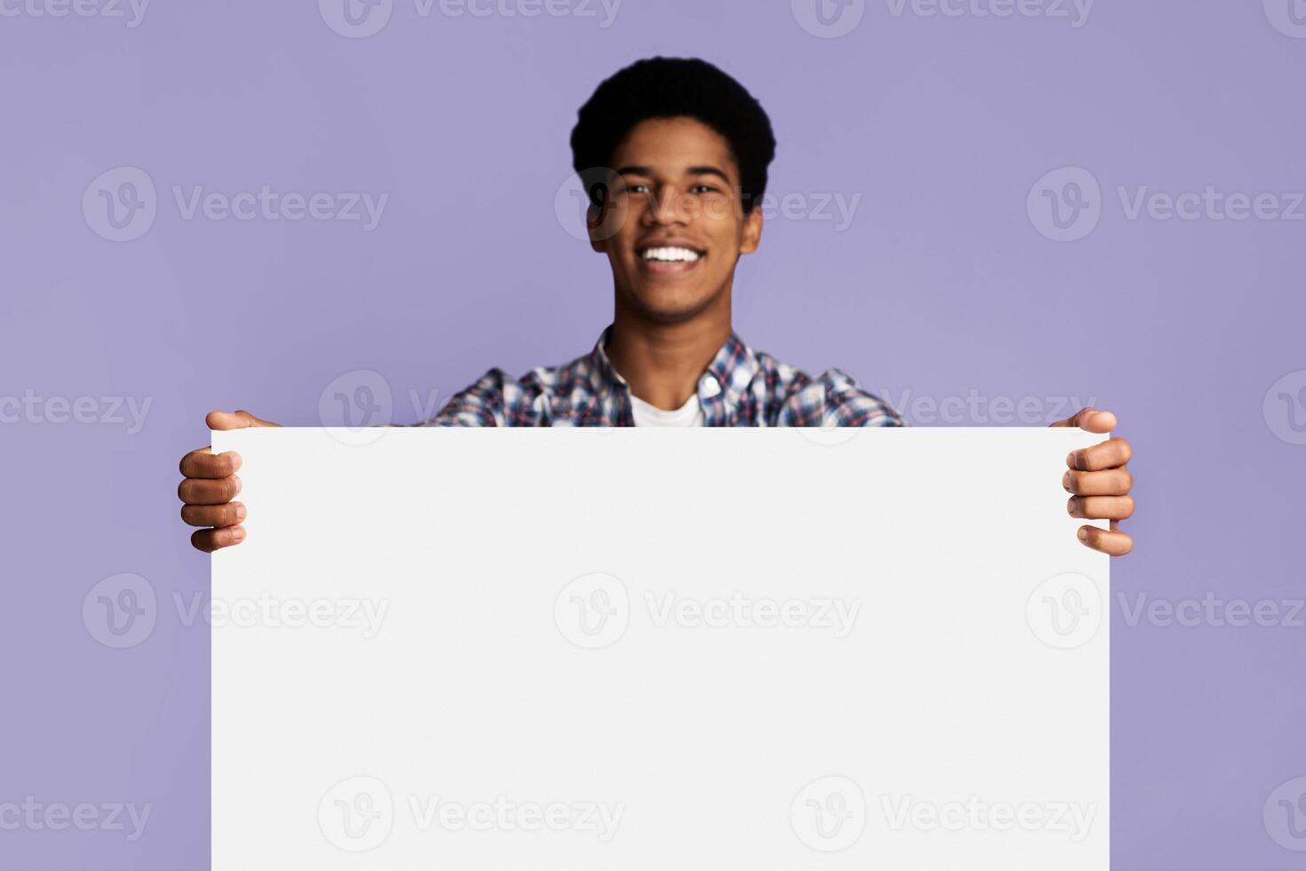 Excited afro guy showing blank banner with free space for your text, pink background photo