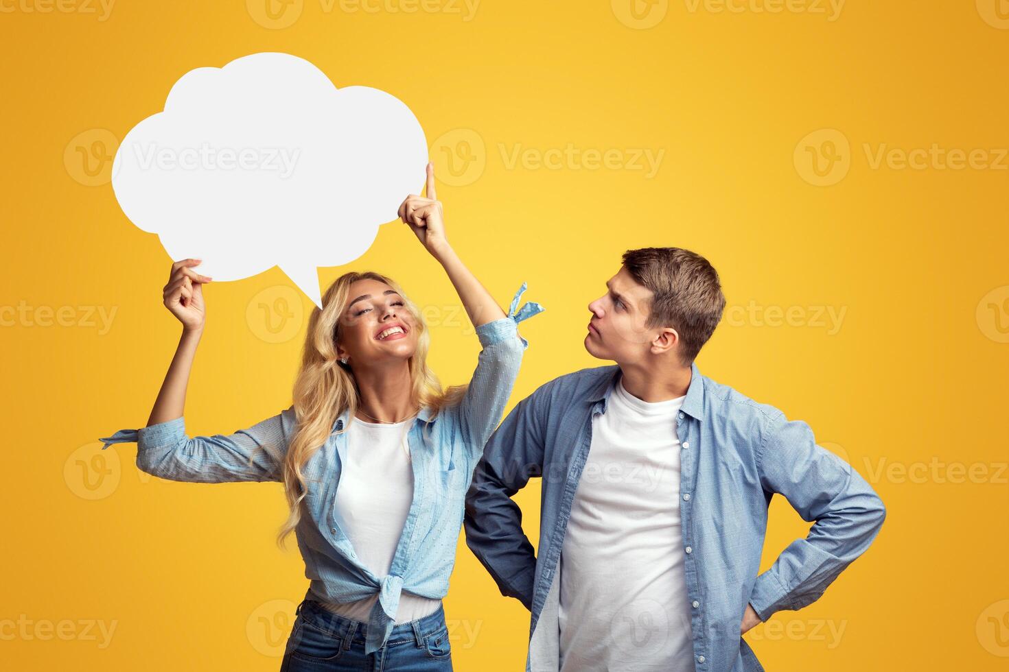 Happy blonde girl holding speech bubble over her head, curious guy trying to guess what she thinking. Copy space photo