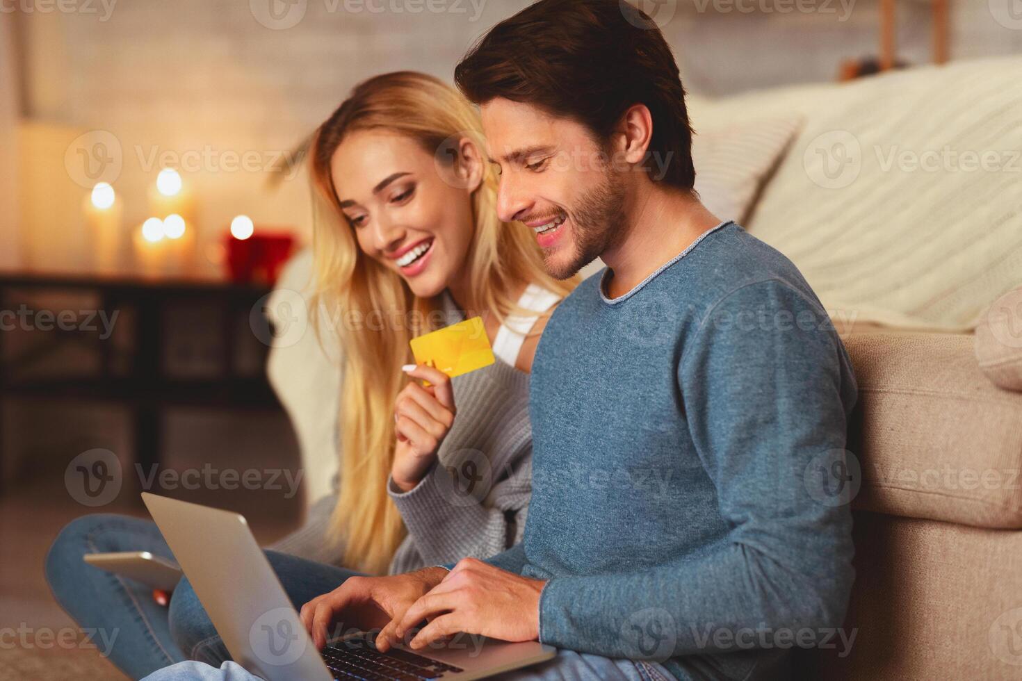 Online Order. Boyfriend And Girlfried Holding Laptop And Credit Card Shopping On The Internet Sitting Indoor. Selective Focus photo