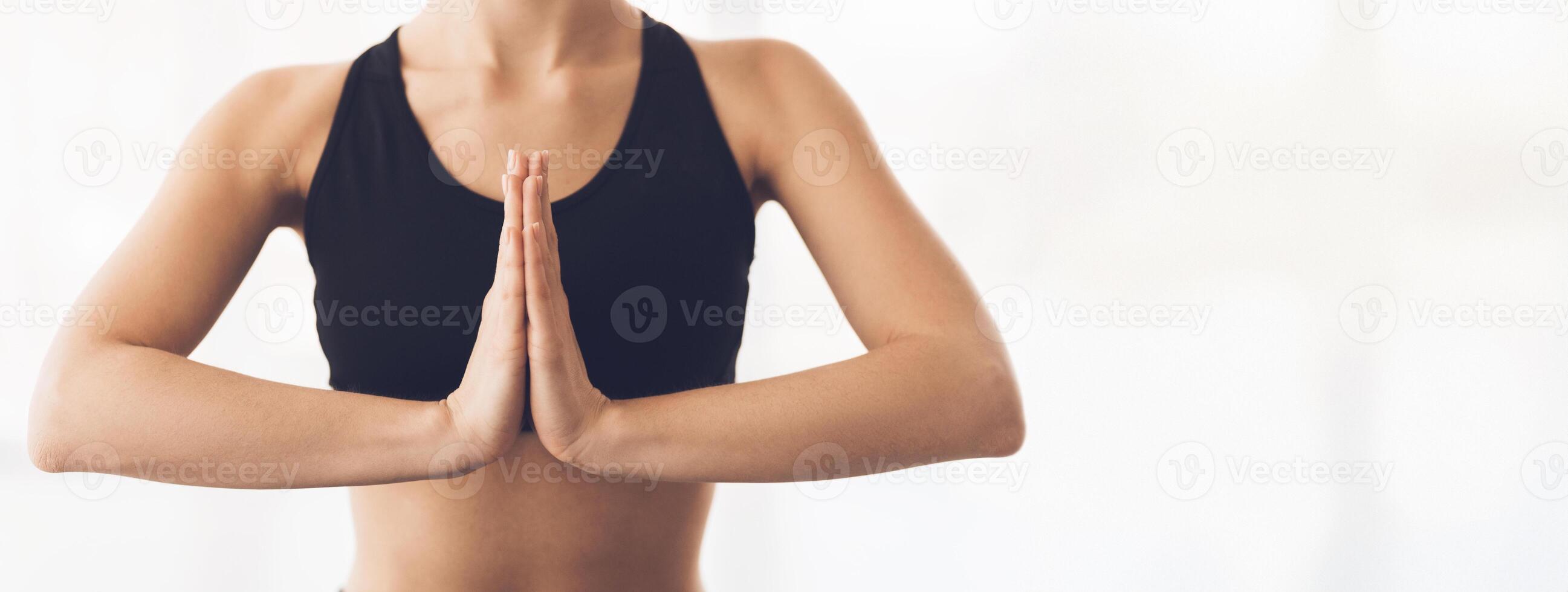 A person performs a yoga pose with hands in a prayer position, showcasing focus and tranquility in a bright, calming environment, copy space, cropped photo