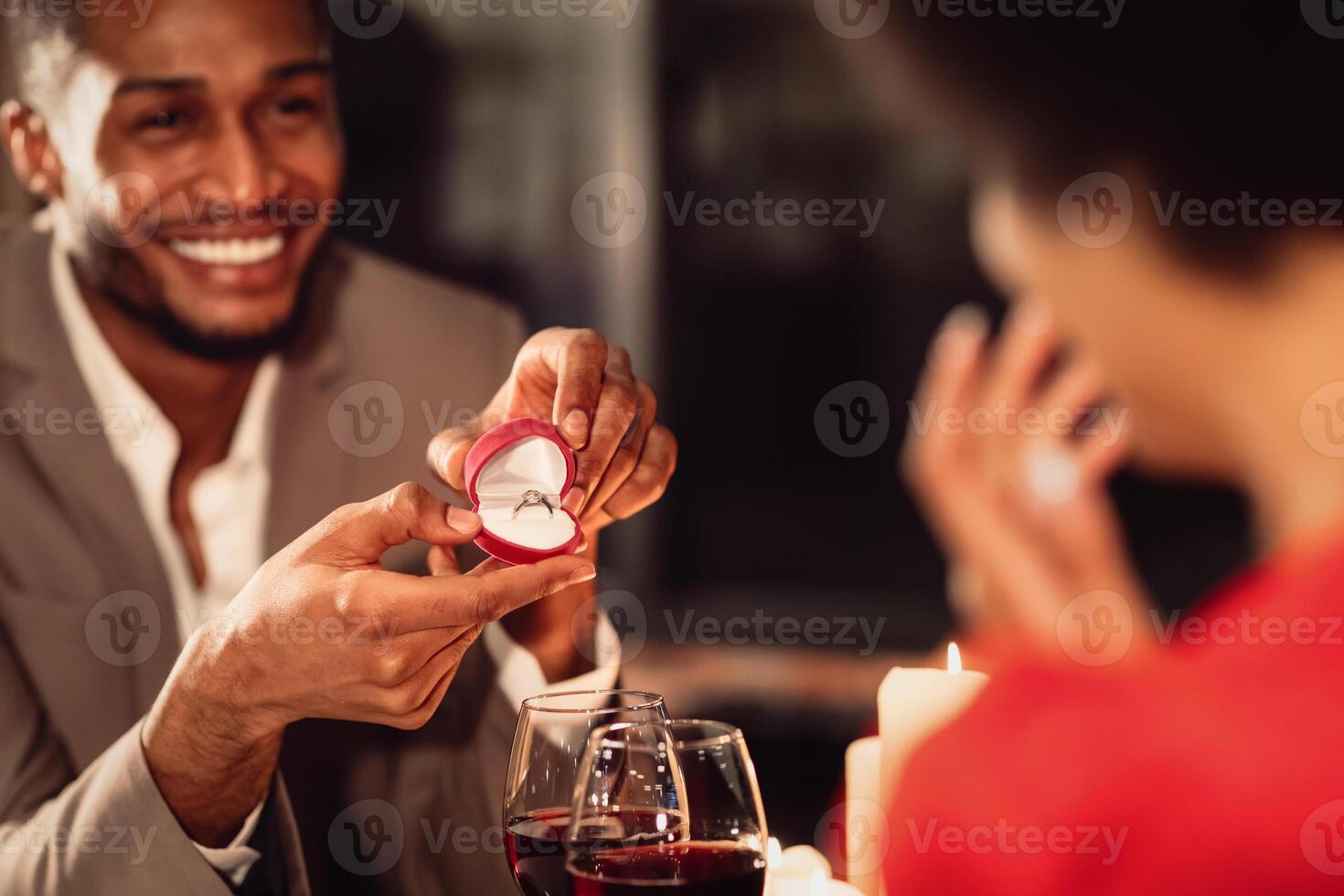 Valentine's Day Proposal. Happy Afro Man Giving His Girlfriend Engagement Ring Asking To Marry Him During Romantic Date In Restaurant photo
