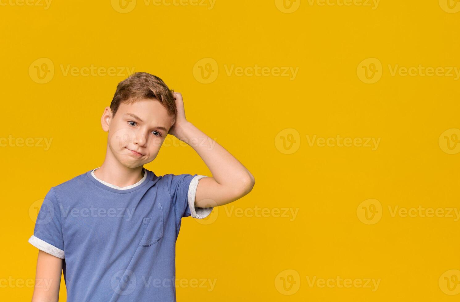 Teenage troubles. Confused boy scratching his head with puzzled expression, orange background. photo