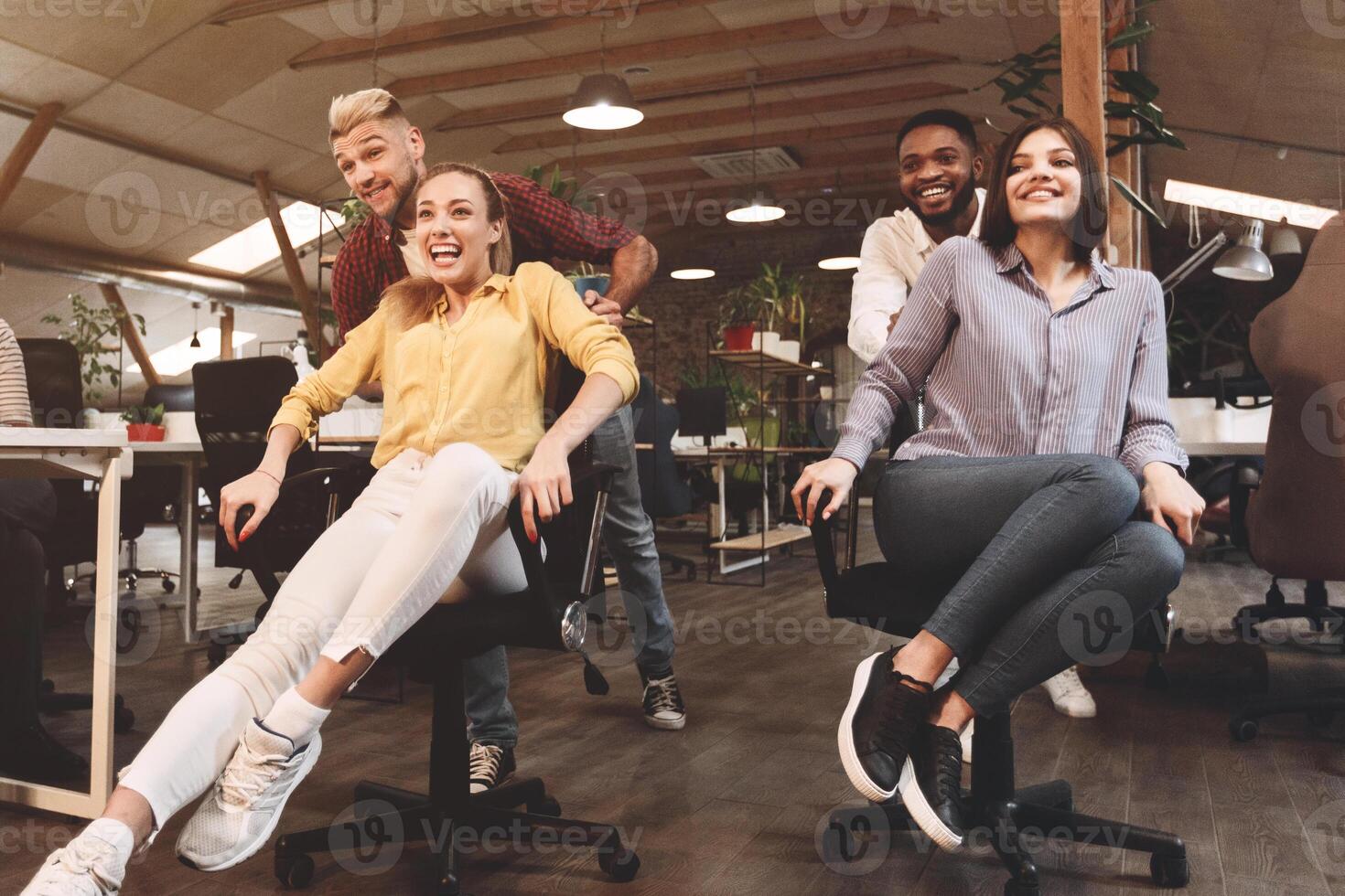 Work hard play hard. Business people having fun, racing on office chairs photo