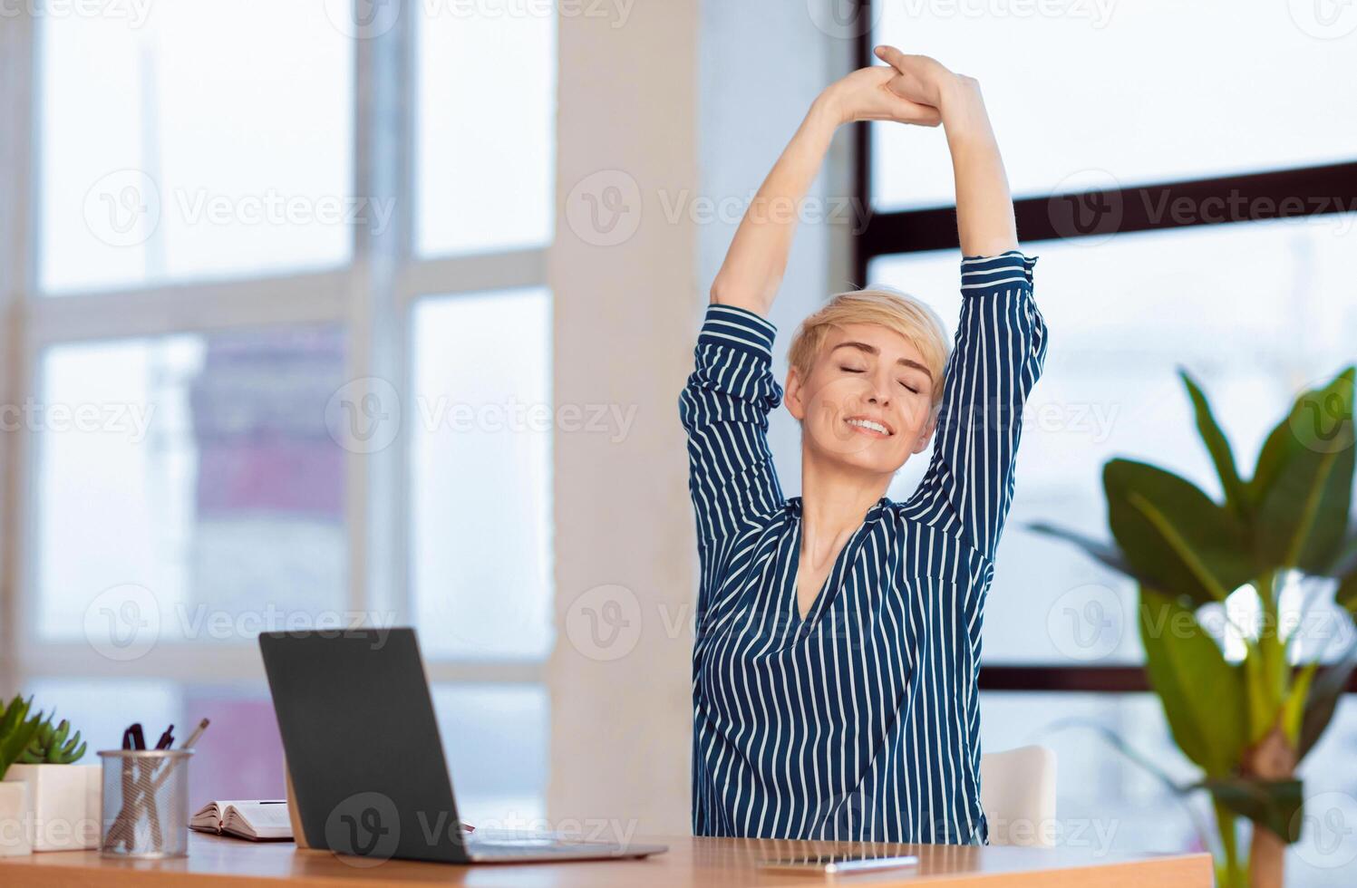 Break At Work. Entrepreneur Lady Stretching Hands With Eyes Closed Working At Laptop Sitting In Modern Office. Selective Focus photo