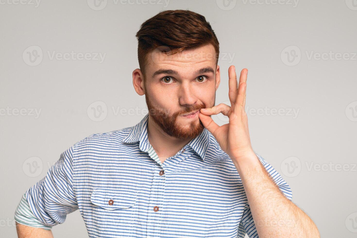 Secret saver. Young guy locking mouth like zip-lock on studio background, panorama, copy space photo