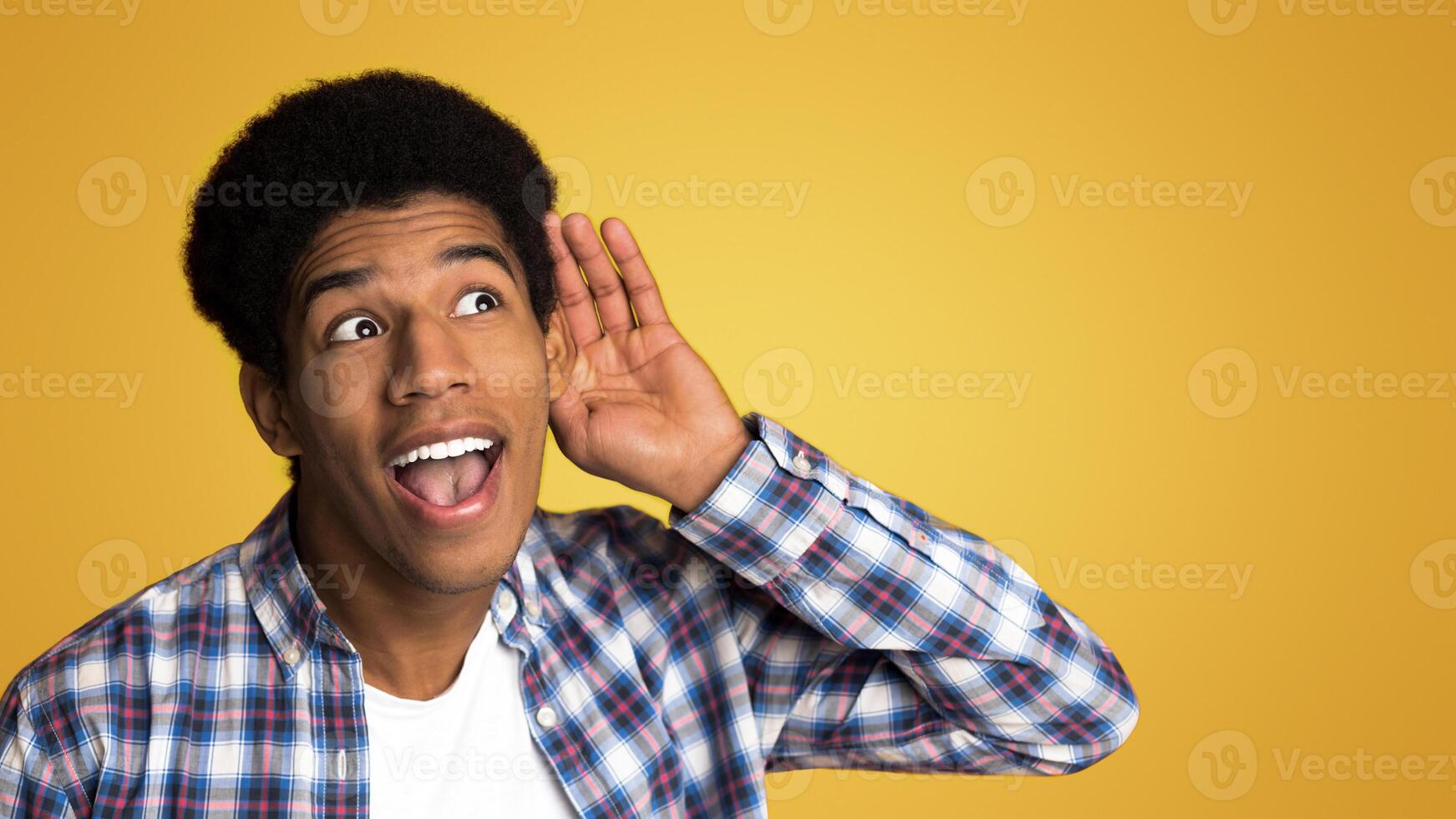 Interested guy trying to hear information, holding hand near ear over studio background photo