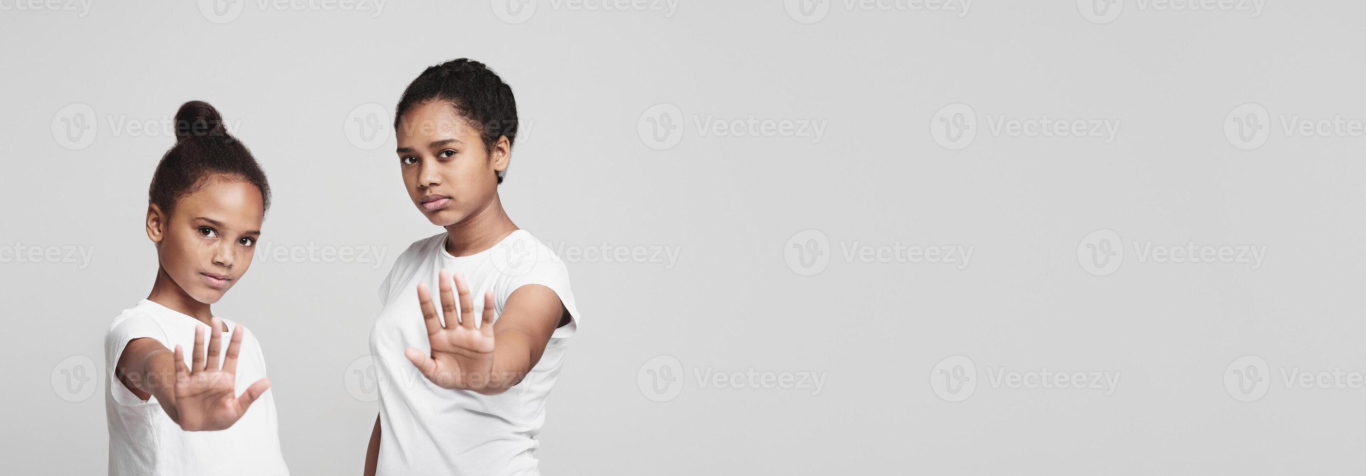 Beautiful african teenaged girls showing no sign over grey studio background photo