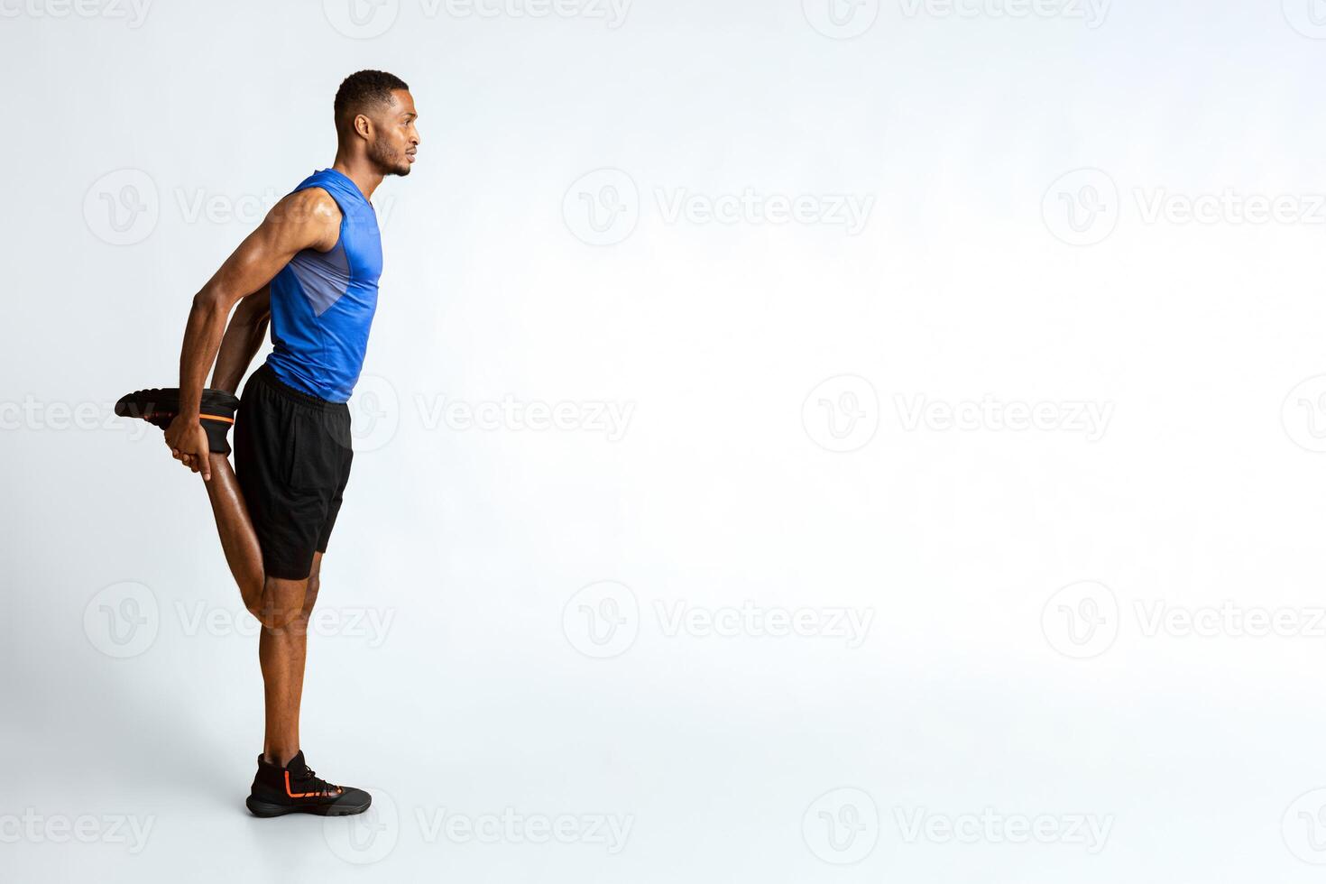 Warm Up. Side view of black man stretching legs before run over yellow studio wall, full length, copyspace photo