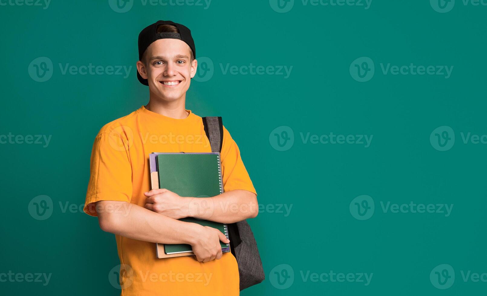 Happy student with books and backpack over turquoise background, copy space photo