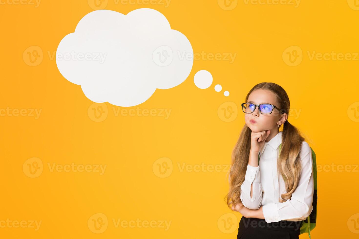 Thoughtful Elementary Schoolgirl Thinking Standing Over Yellow Background In Studio. Free Space For Text photo