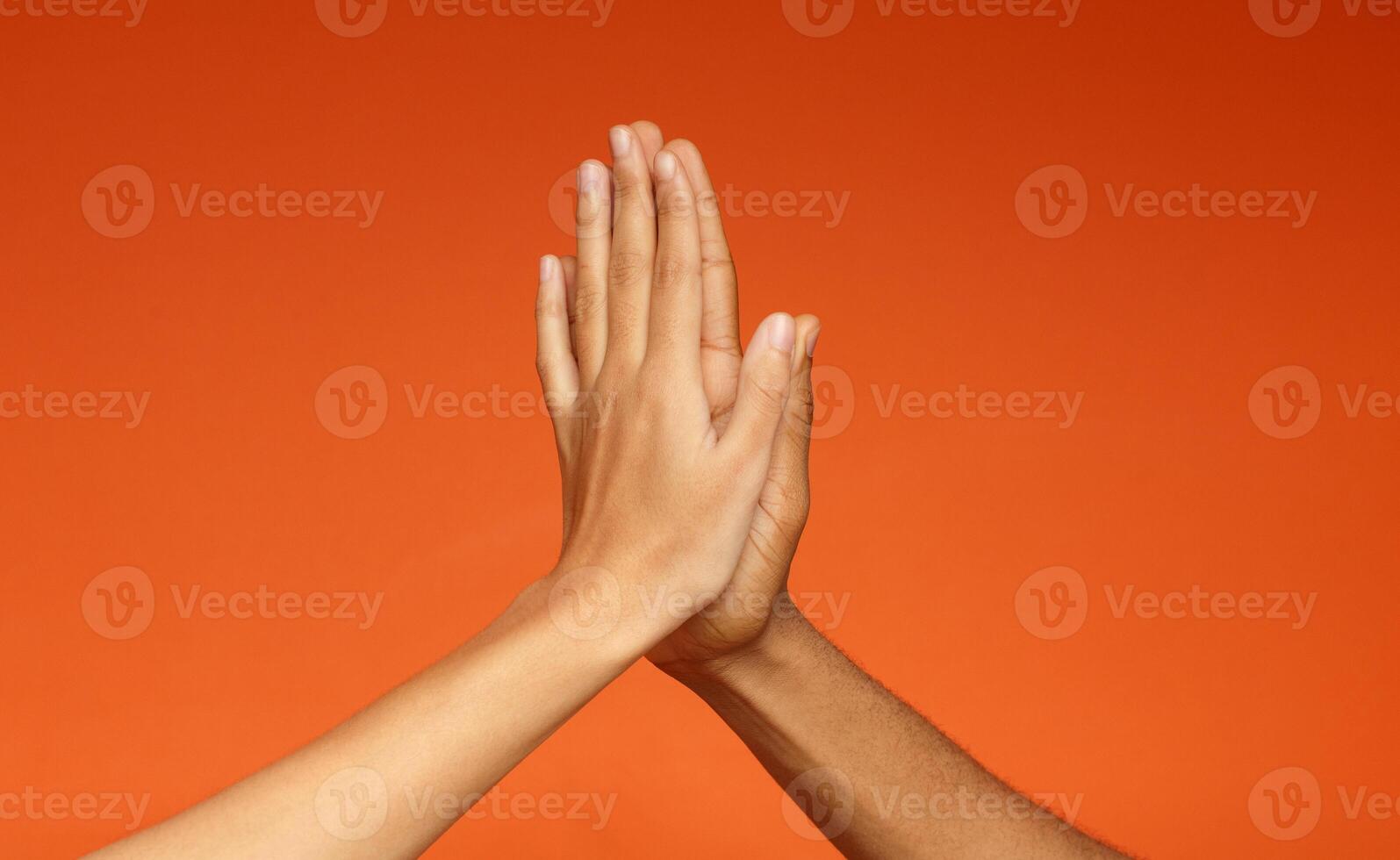 African-american man and woman greeting each other with high five, clapping hands on orange background photo