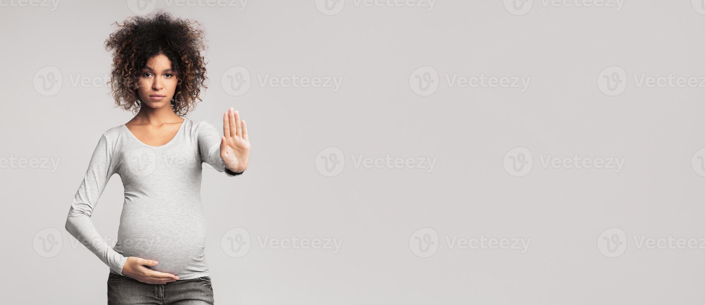 African-american pregnant woman gesturing stop and looking at camera, grey background photo