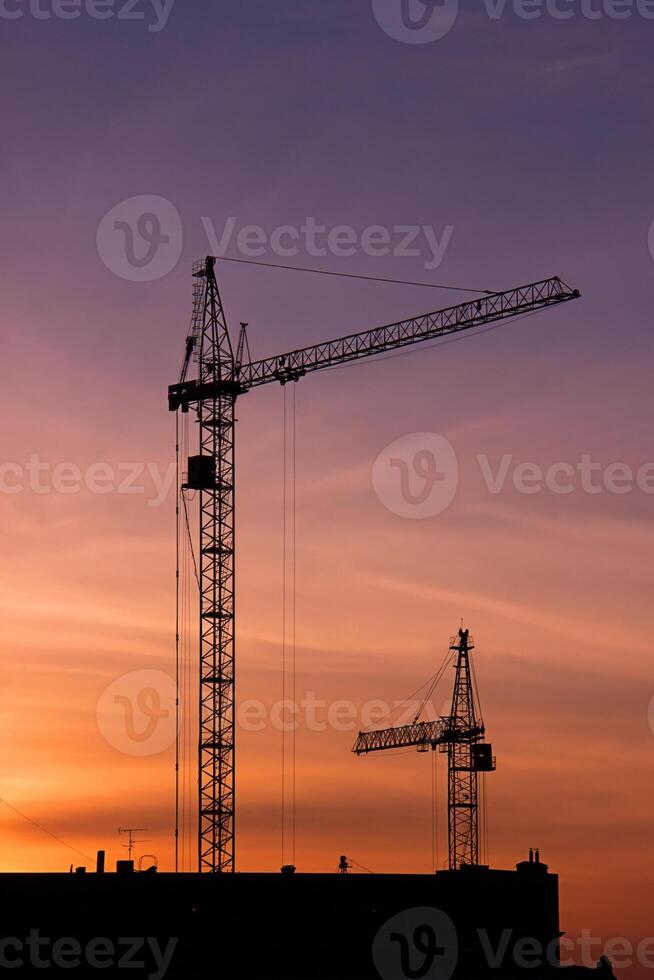 Shadows of two construction cranes on a sunset background. photo