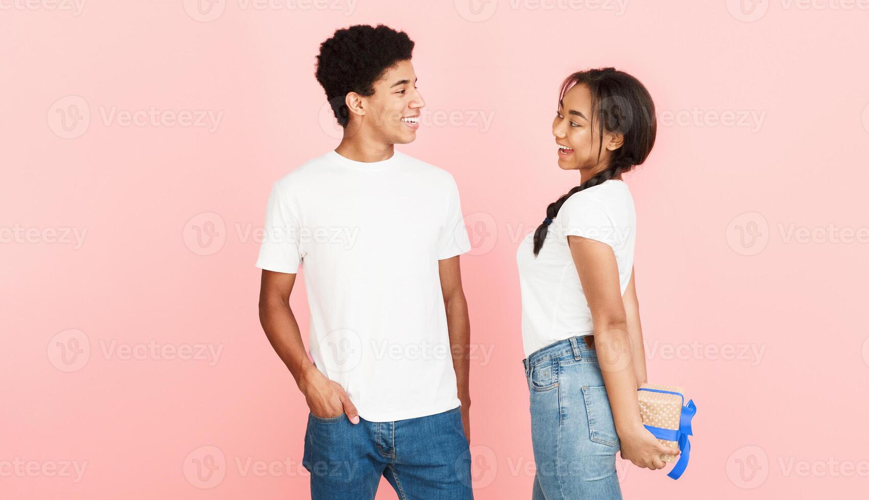 I have surprise. Girl hiding present from boyfriend over pink background photo