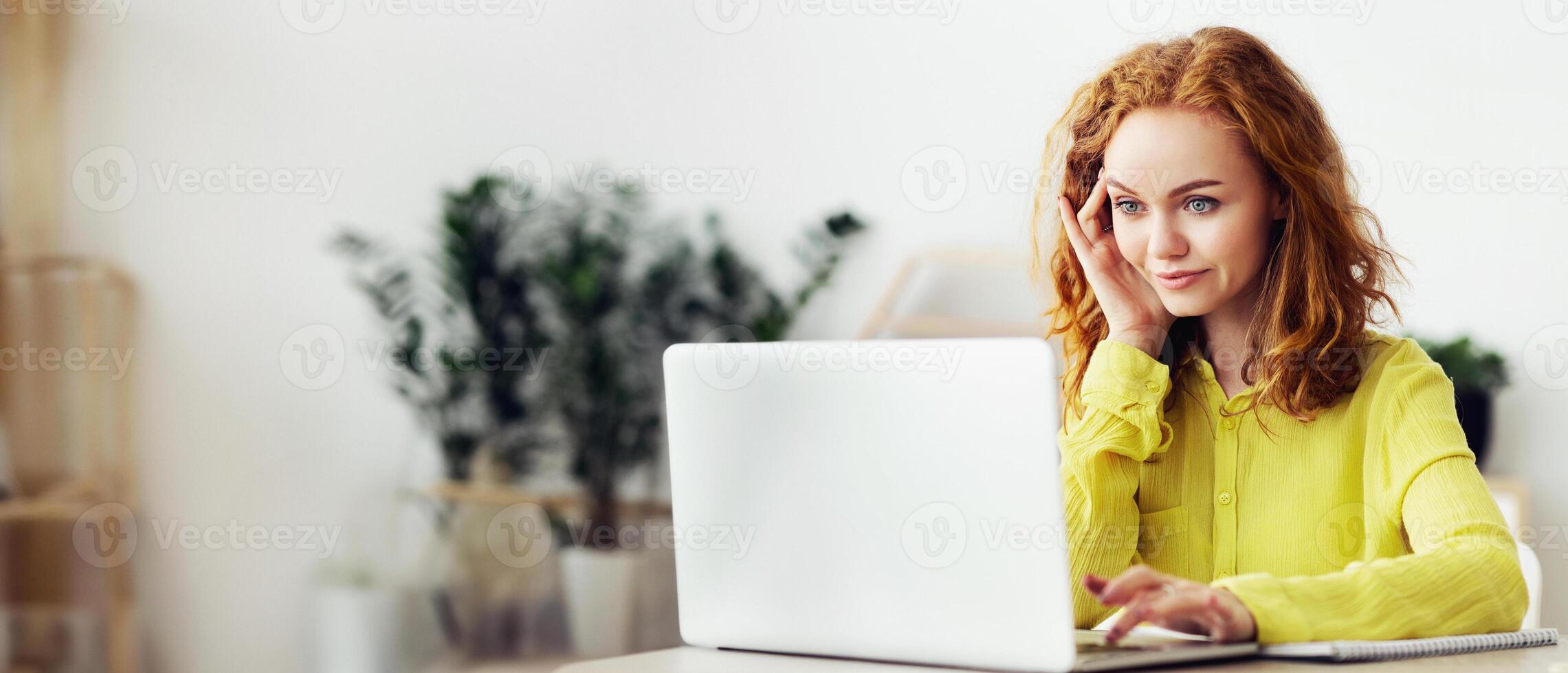 Working At Home Concept. Smiling young curly female manager typing on computer, doing remote job, copy space photo
