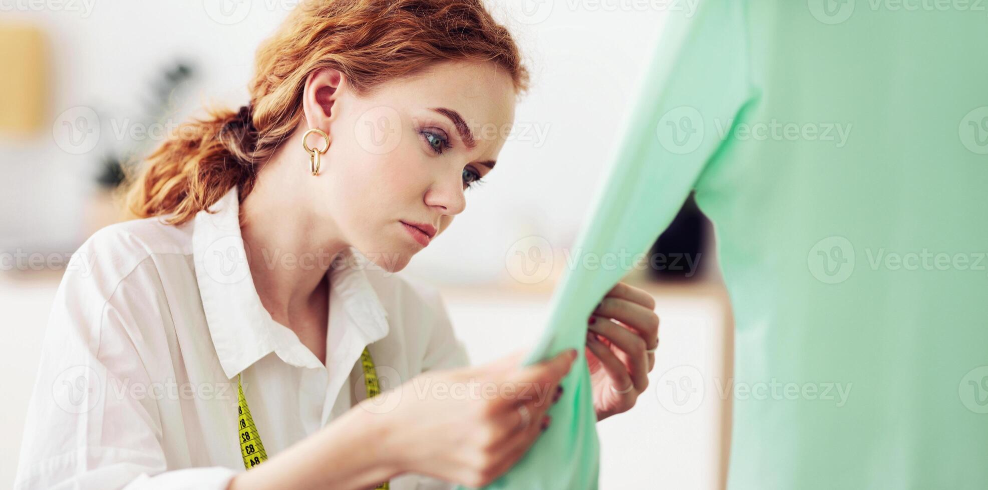 Serious tailor touching and checking new sweater, working in own atelier photo