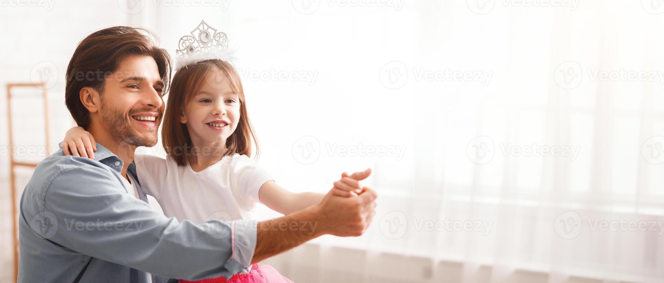 Close up of handsome cheerful father dancing with his princess daughter indoor, happy to be father, copy space photo