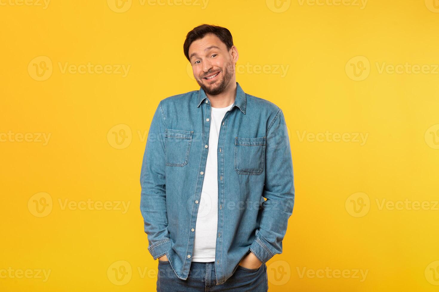 A man is standing upright in front of a vibrant yellow background. He appears confident and focused. The bright color of the backdrop creates a striking contrast with the mans silhouette. photo