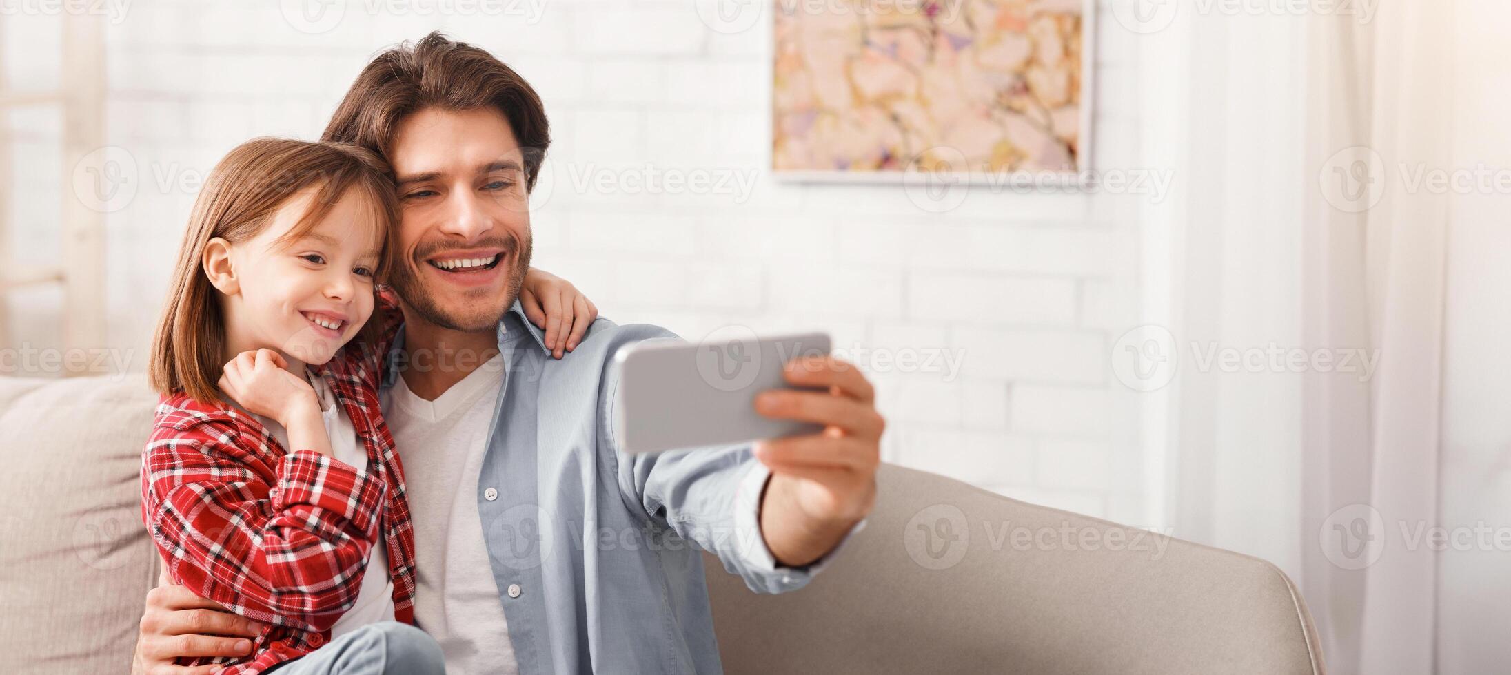 Family portrait. Father and daughter taking selfie on smartphone at home, copy space photo
