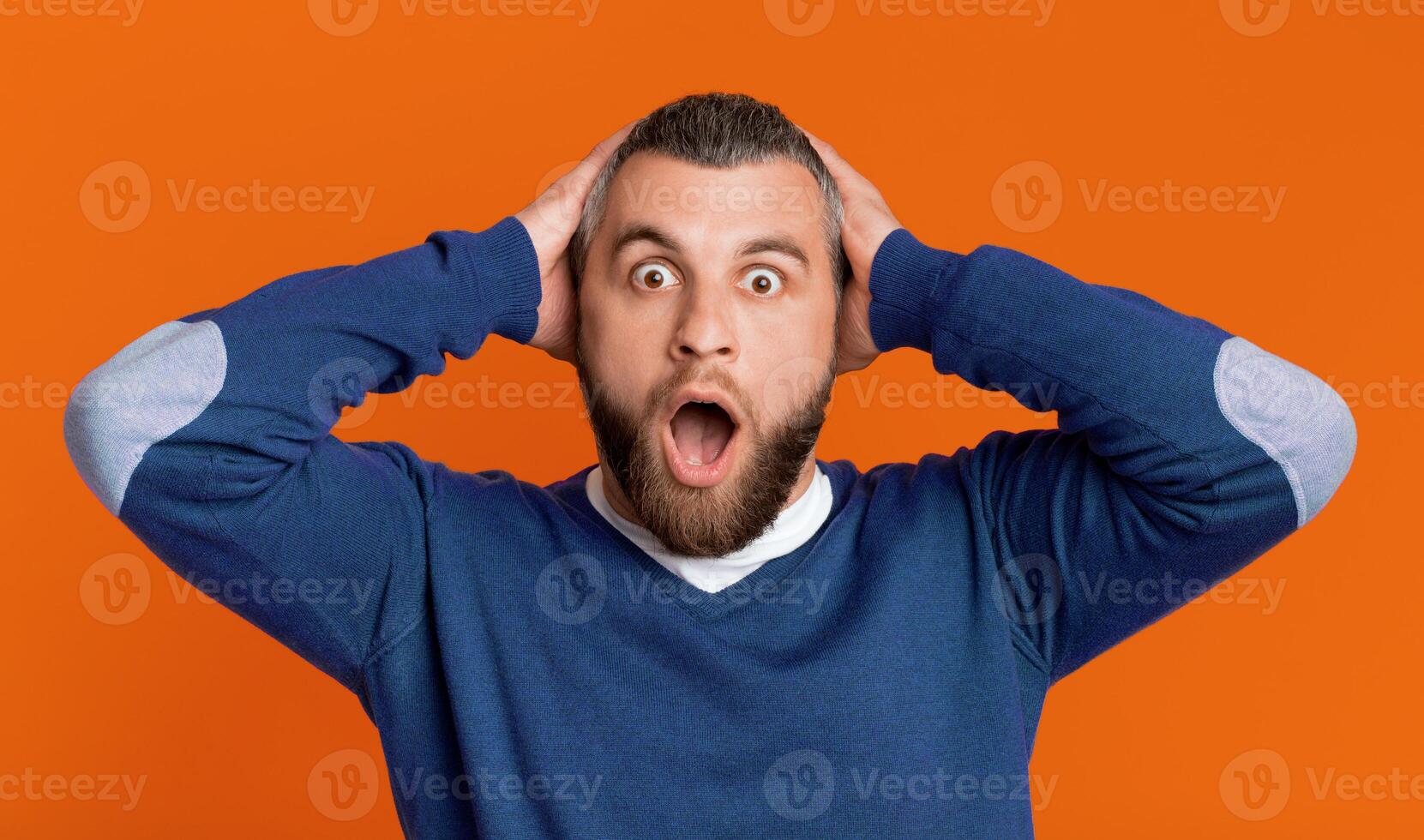 A man with a surprised expression on his face, his eyebrows raised and mouth slightly open in disbelief. His eyes are wide, showing shock and astonishment at whatever he is seeing or hearing. photo