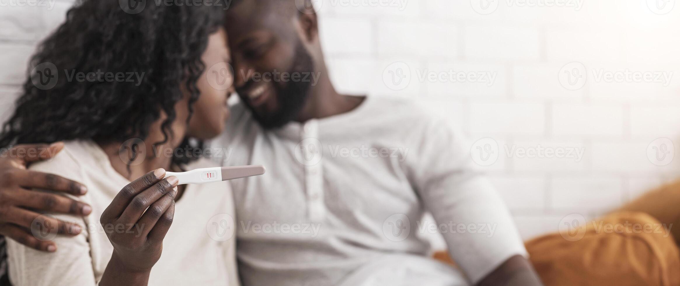We are going to be parents. Happy african american couple holding pregnancy test with positive result, selective focus photo