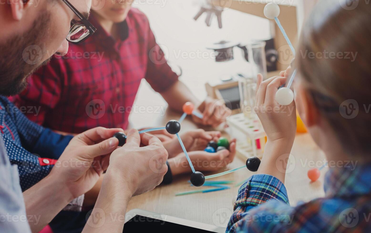 Stem education. Physical experiments at school, kids constructing atom model on lab workplace, copy space. photo