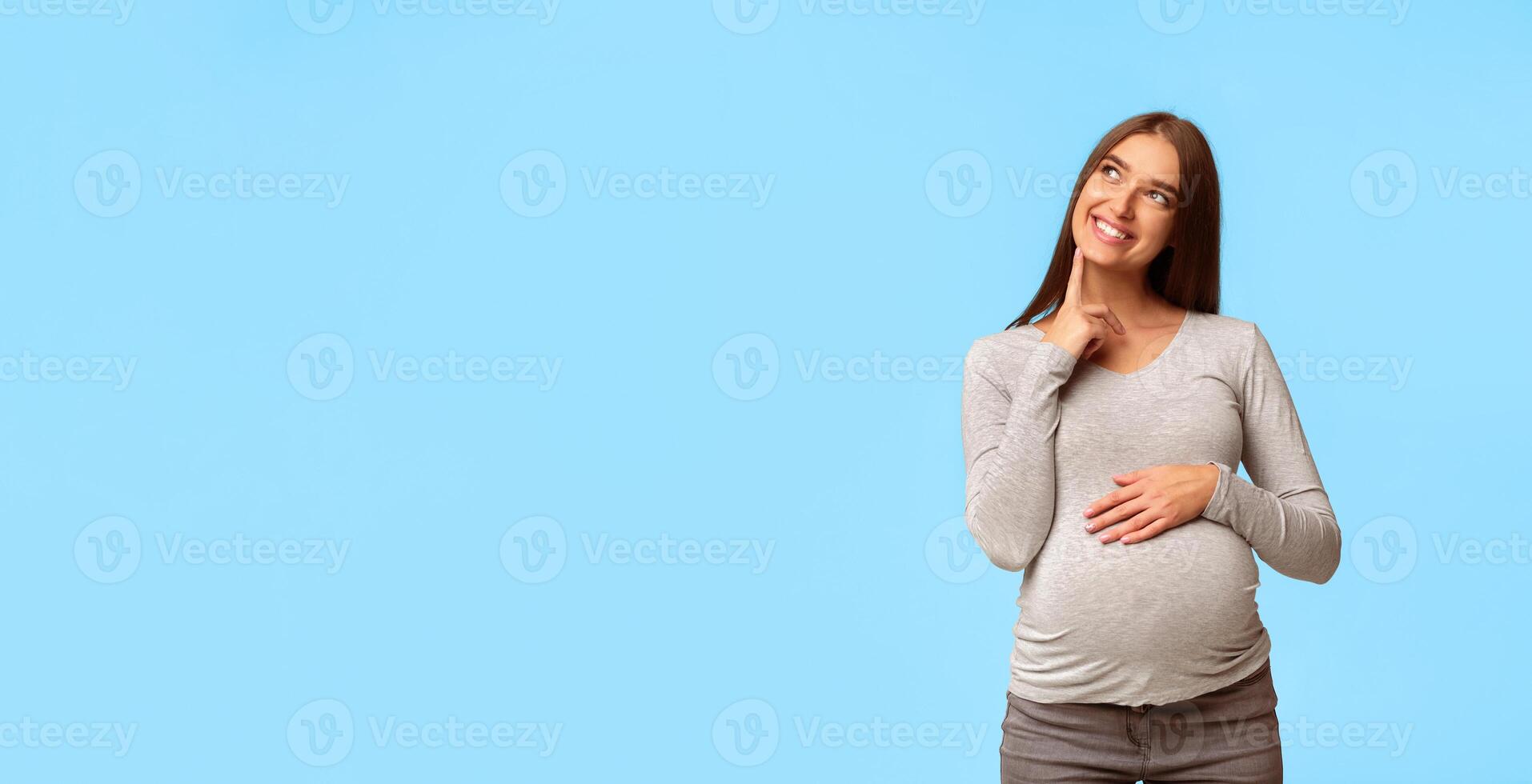 Dream. Happy Pregnant Woman Thinking Imagining Motherhood Life Standing Over Gray Studio Background. Copy Space photo