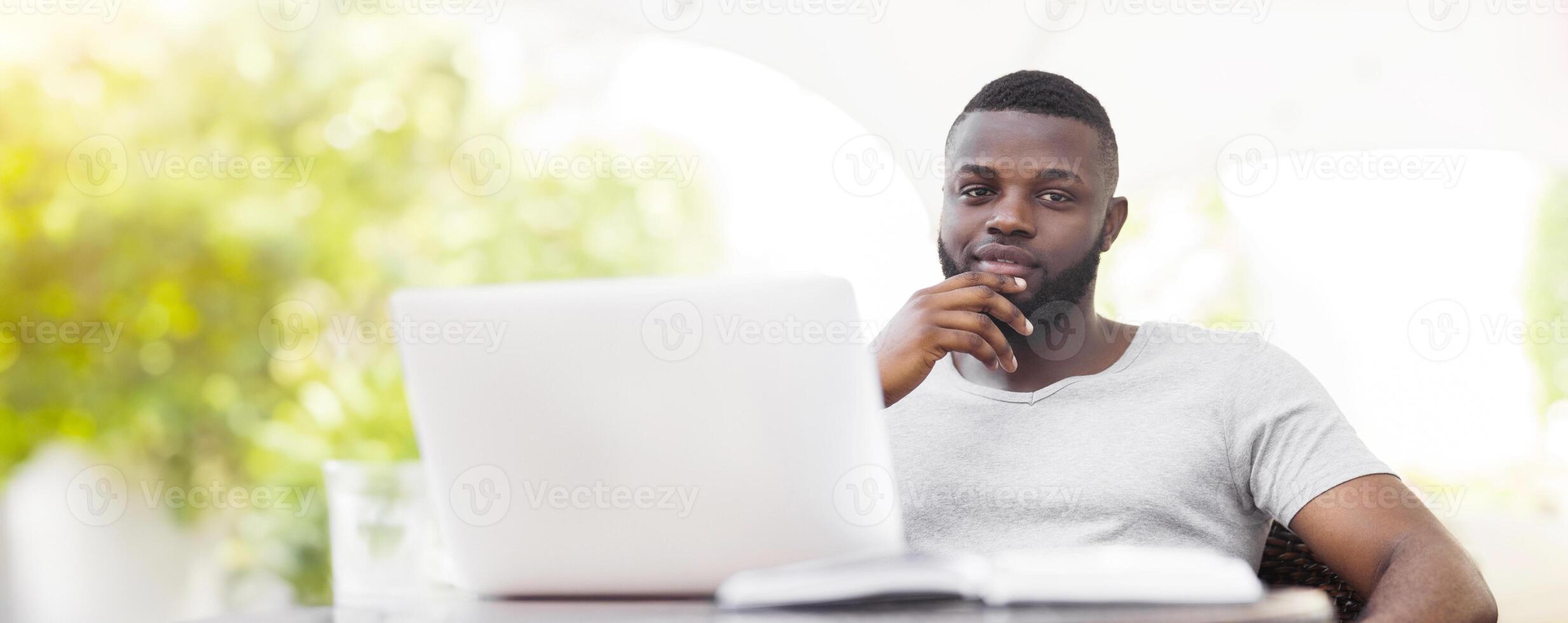 A man with a beard sits in front of a laptop, thinking about his work. photo
